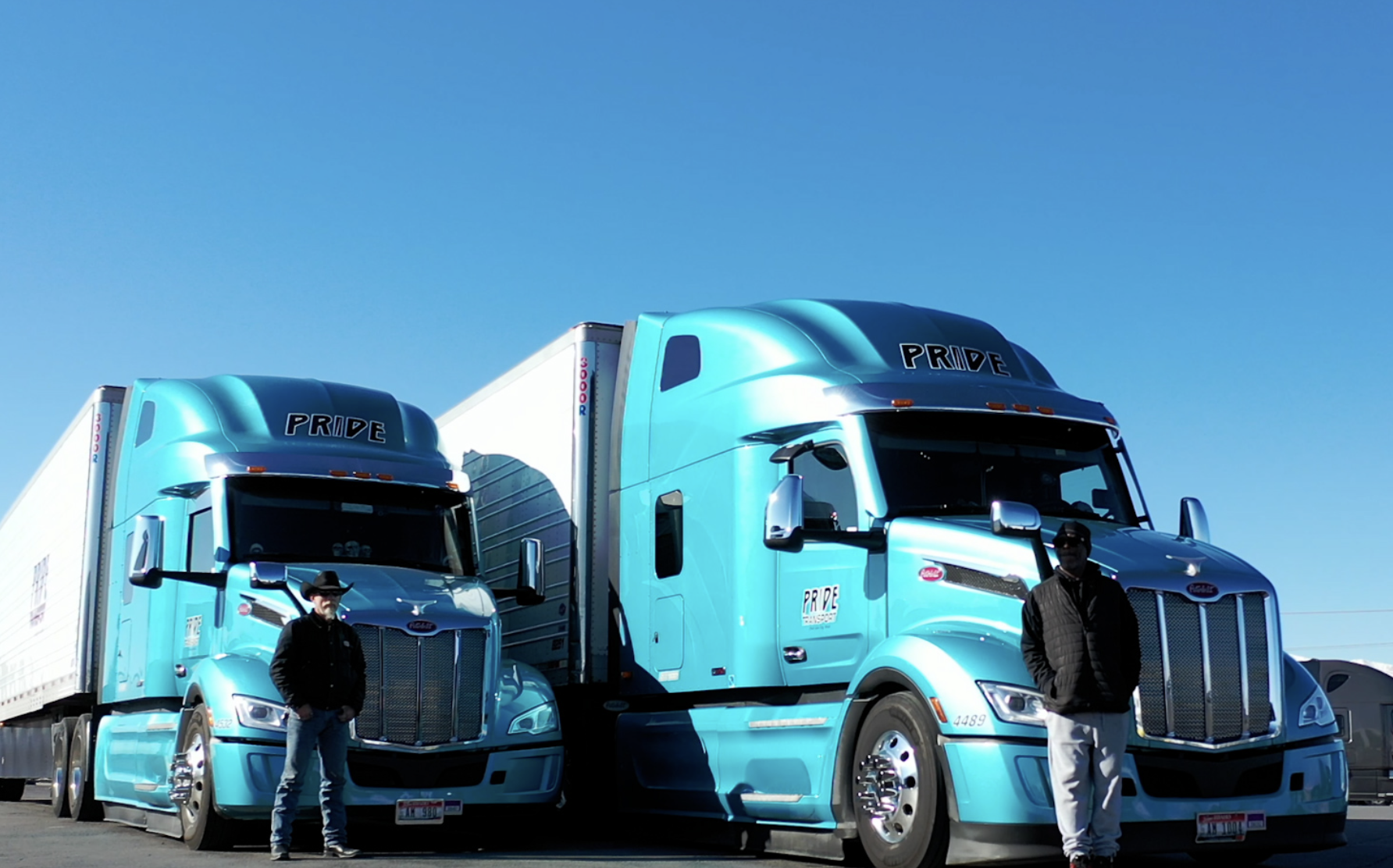 drivers standing in front of pride transport trucks