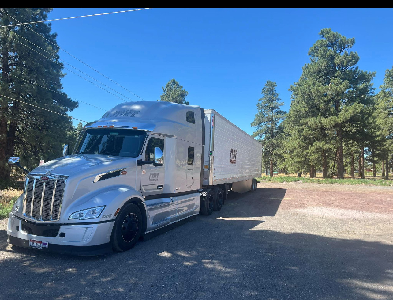 silver pride transport truck in front of trees