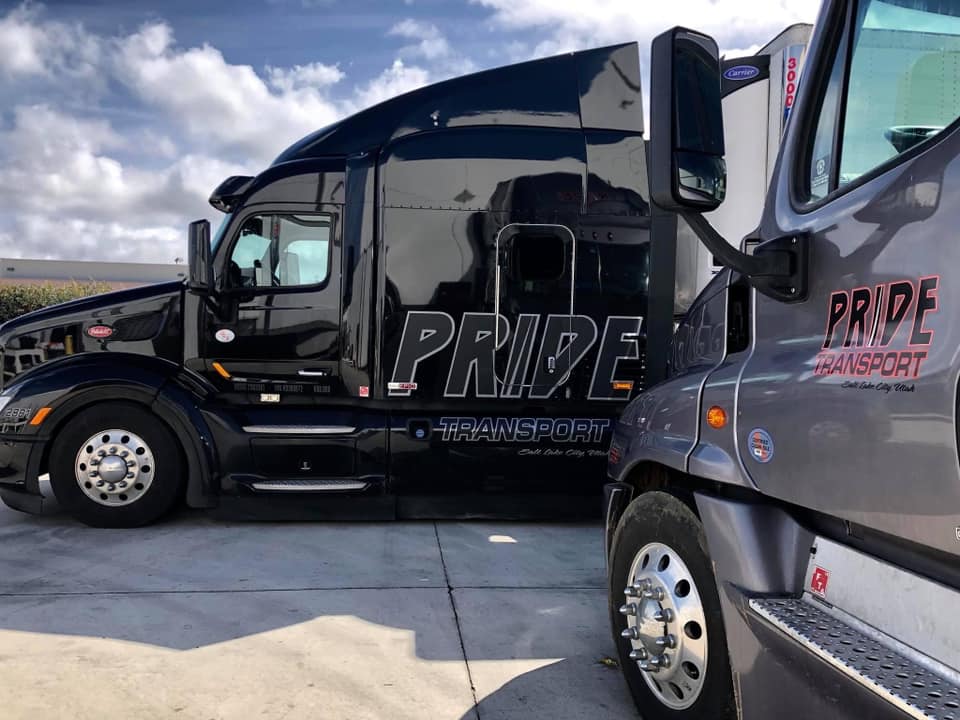 two pride transport trucks parked next to each other