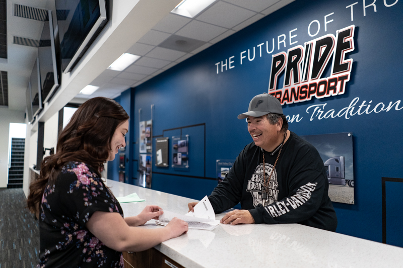 truck driver smiles while being handed paper inside an office