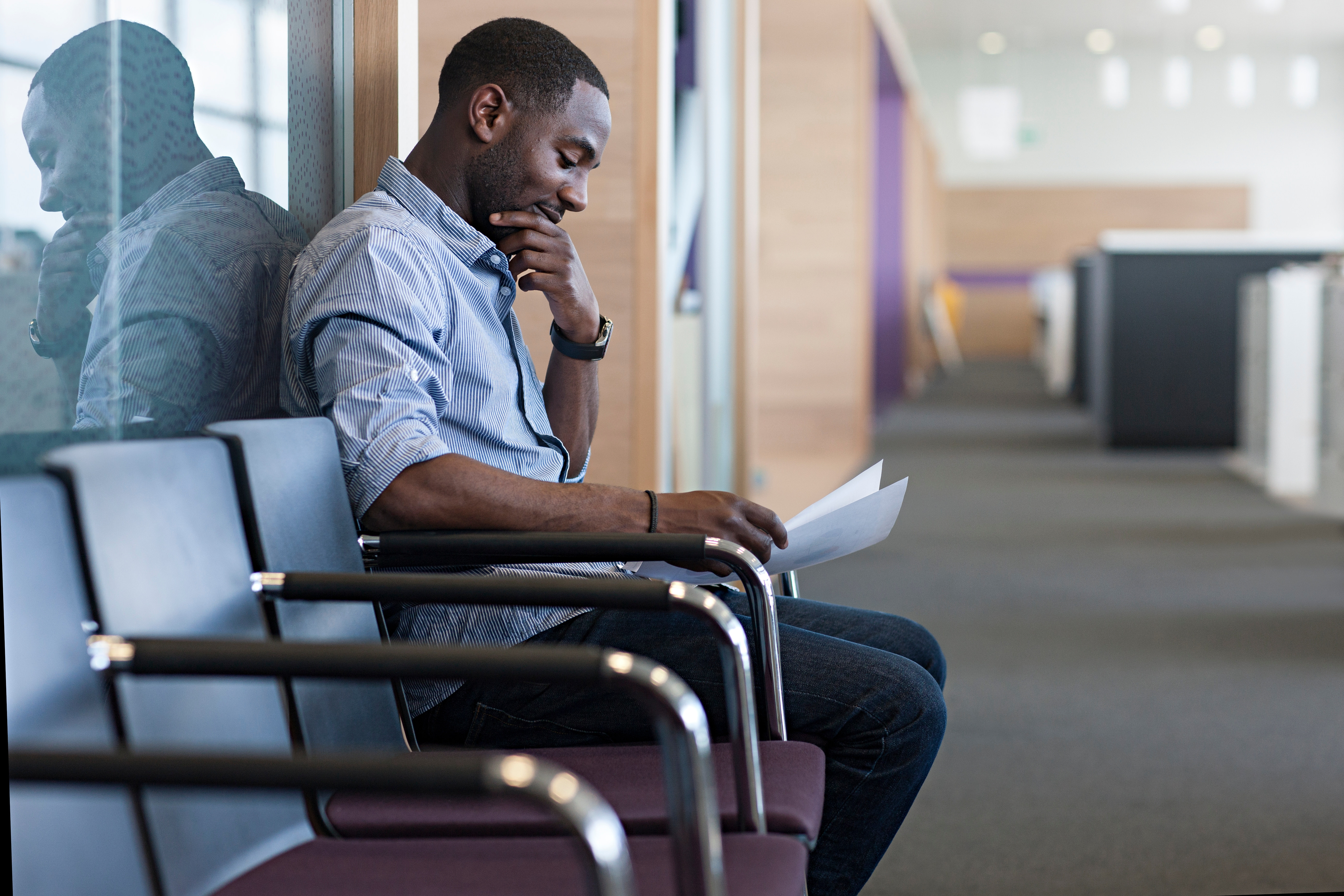 man sitting on a bench and reading a document