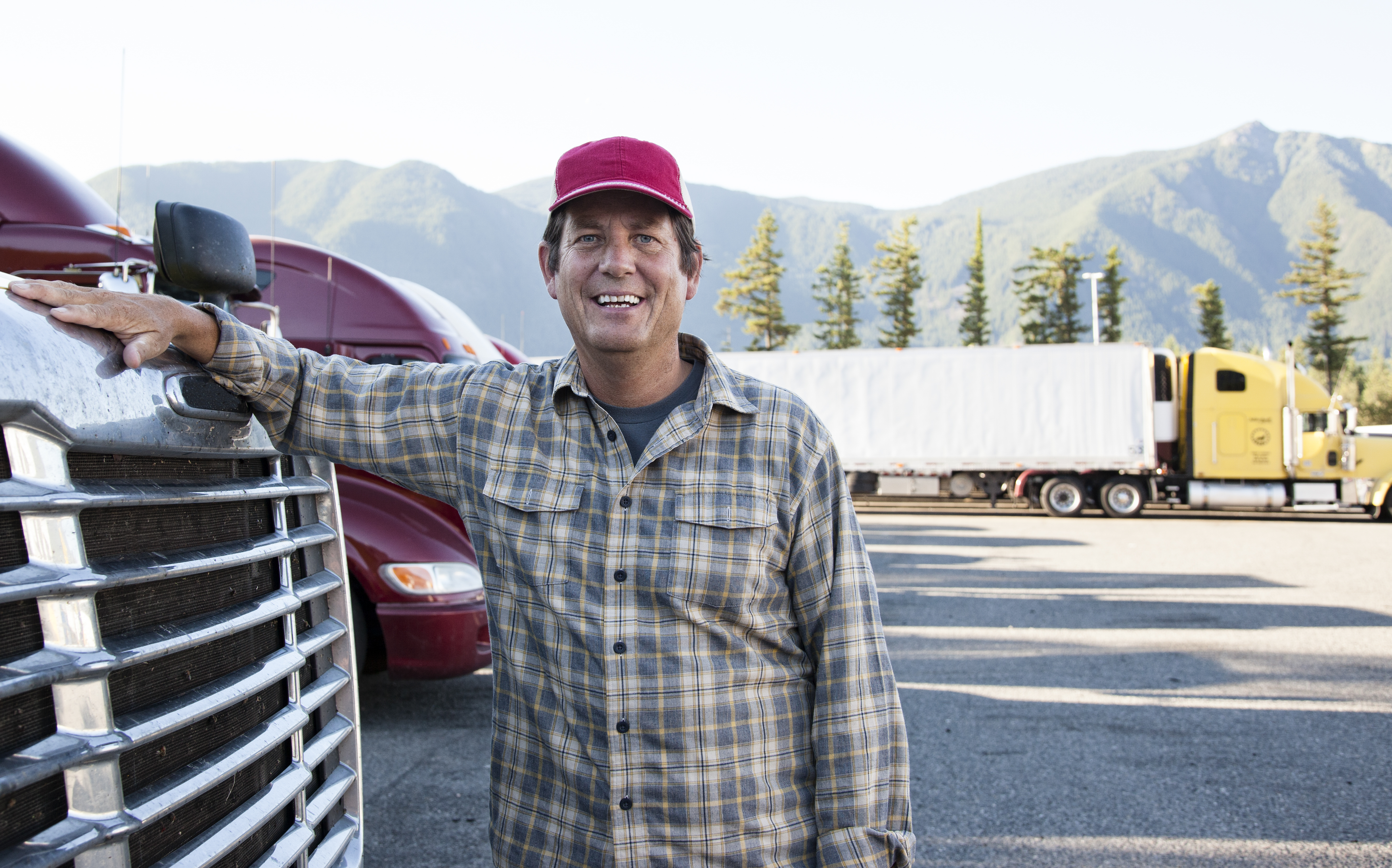 man leaning on an 18 wheeler truck and smiling at the camera