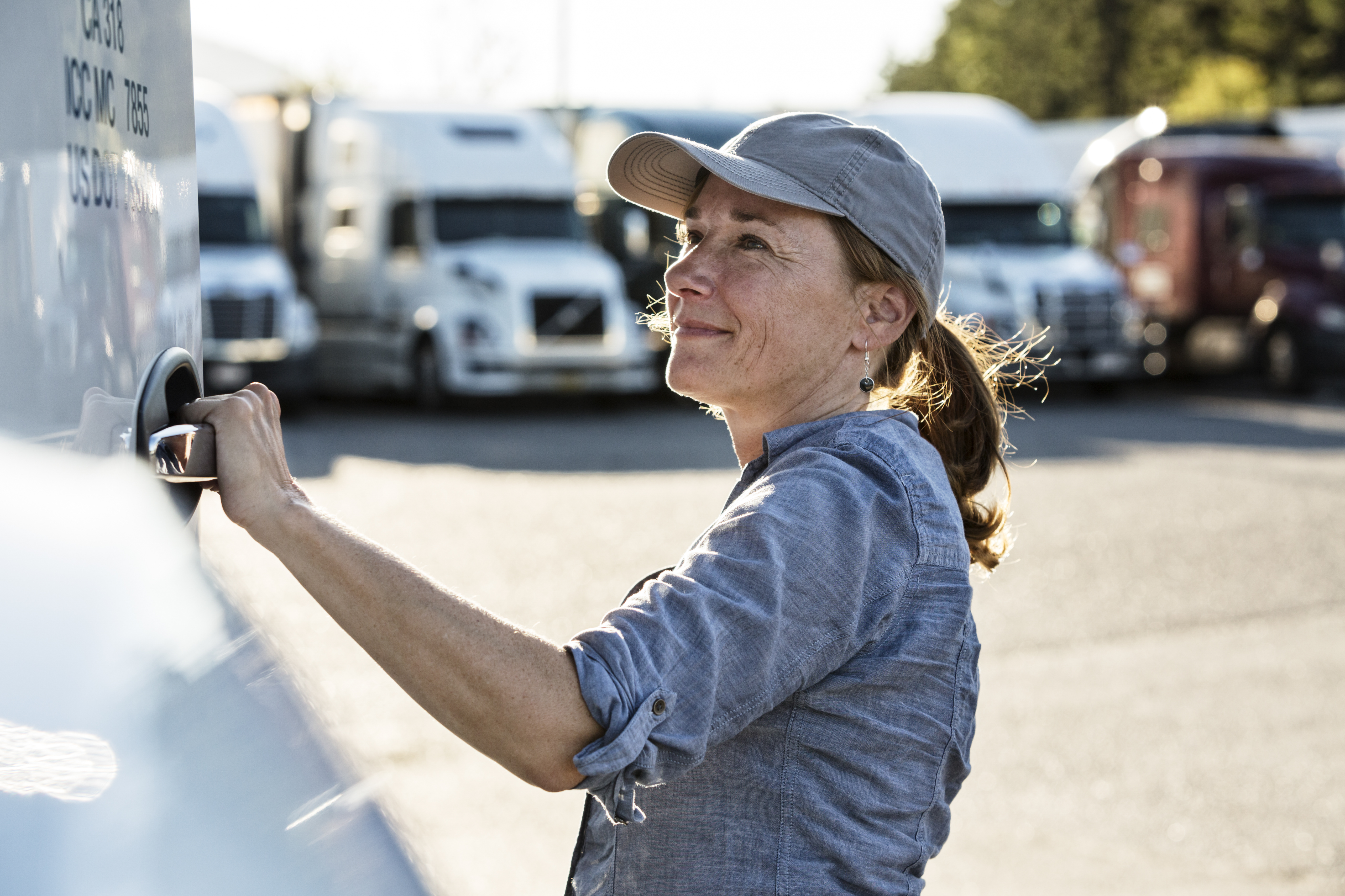 woman trucker standing in front of trucks parking in a lot