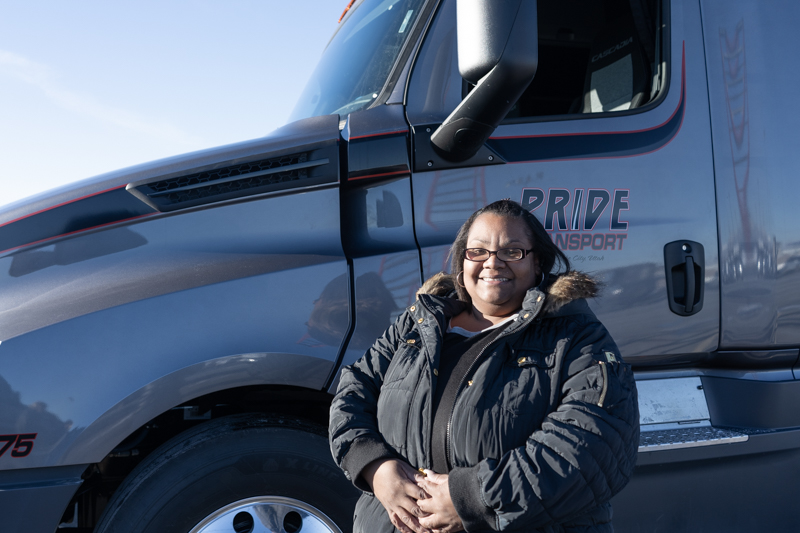 female pride transport employee standing in front of a pride truck