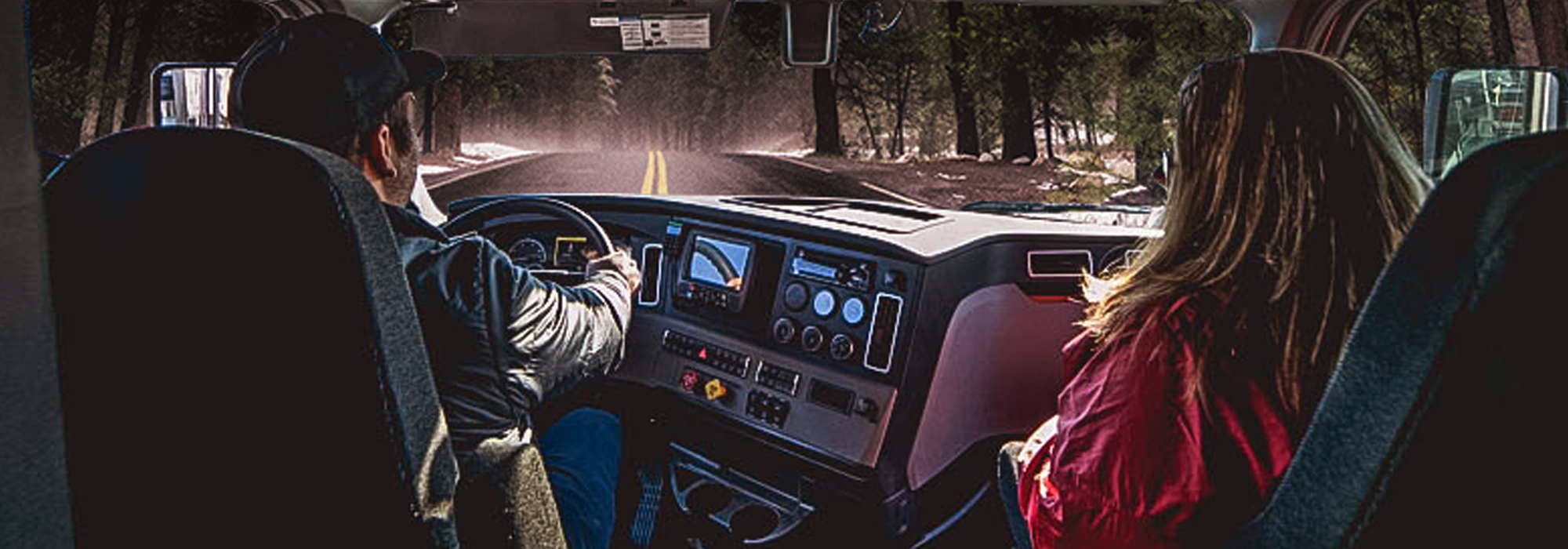 two truck drivers in cab looking out the windshield