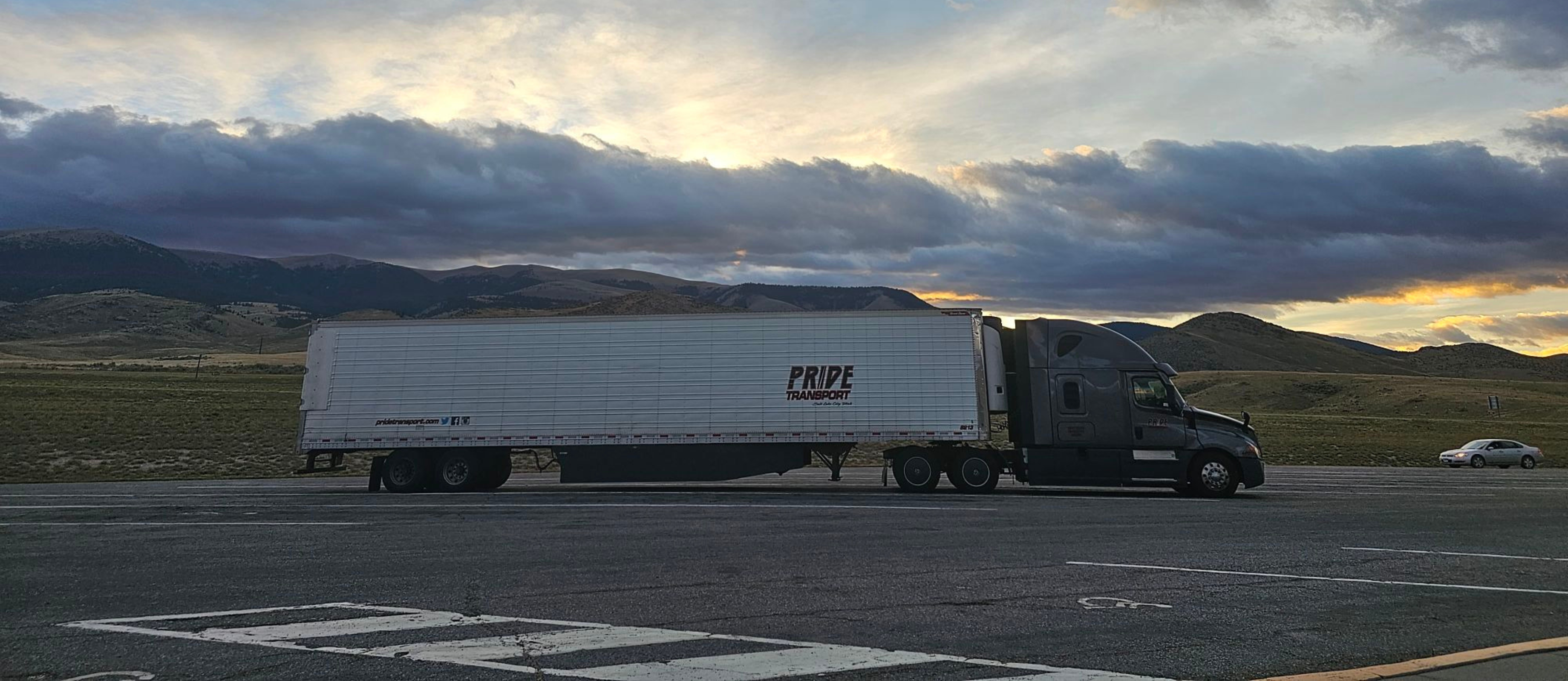 wide side photo of pride transport truck with sunset in background