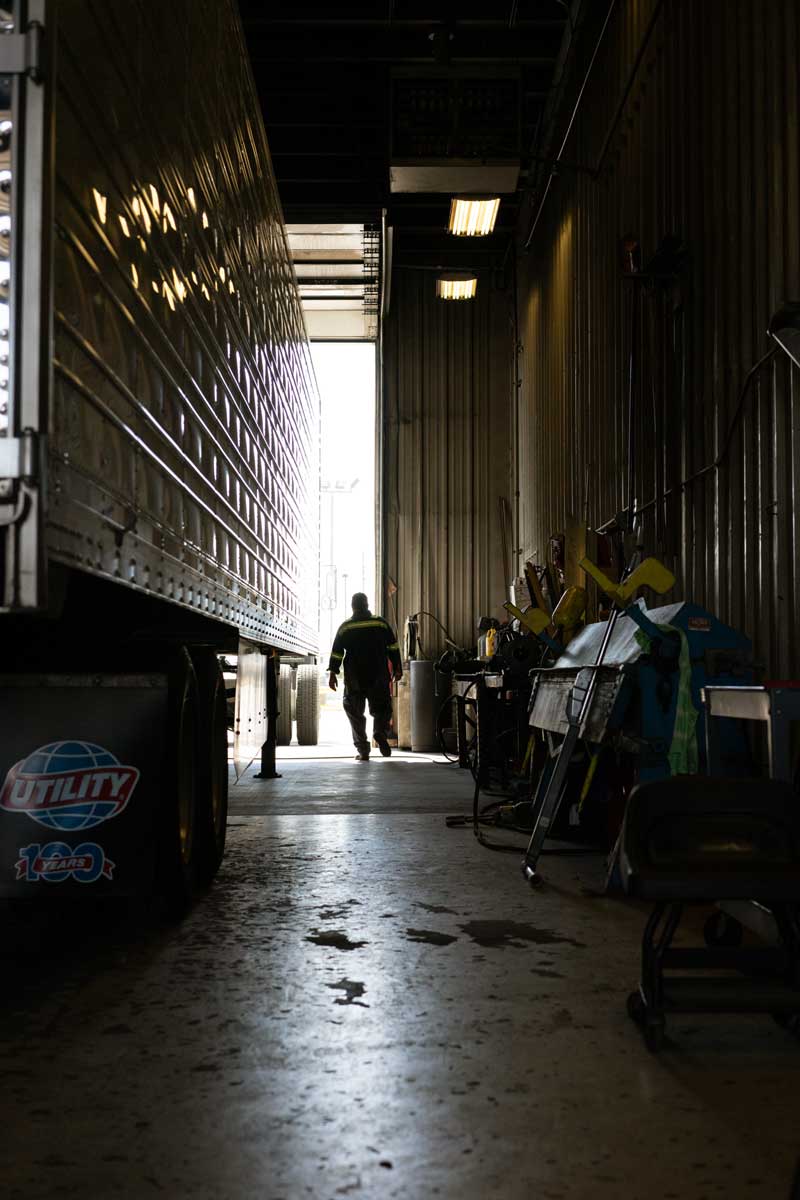 diesel tech walking next to a semi truck trailer in the shop