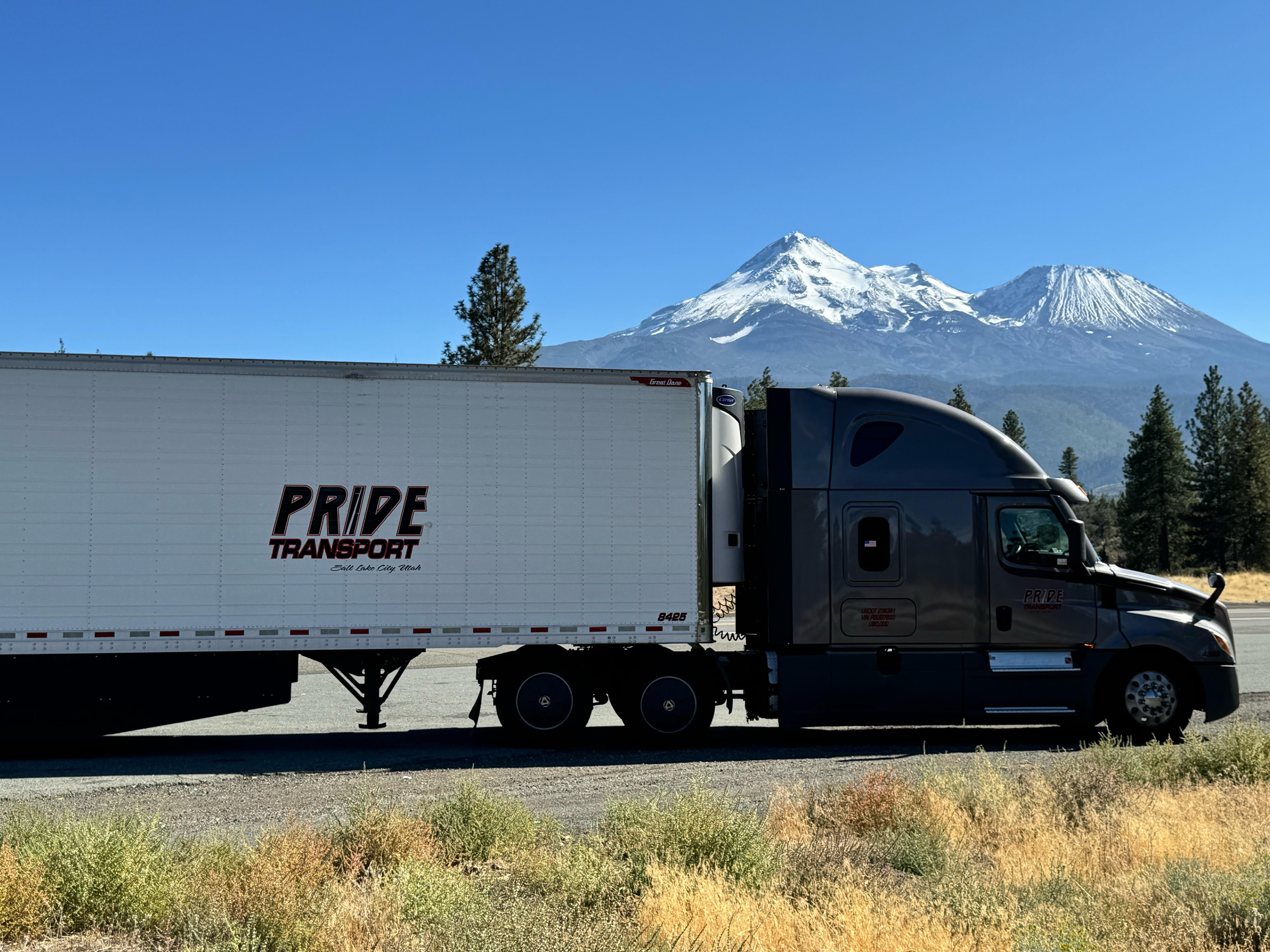pride transport truck parked with snow capped mountain in background
