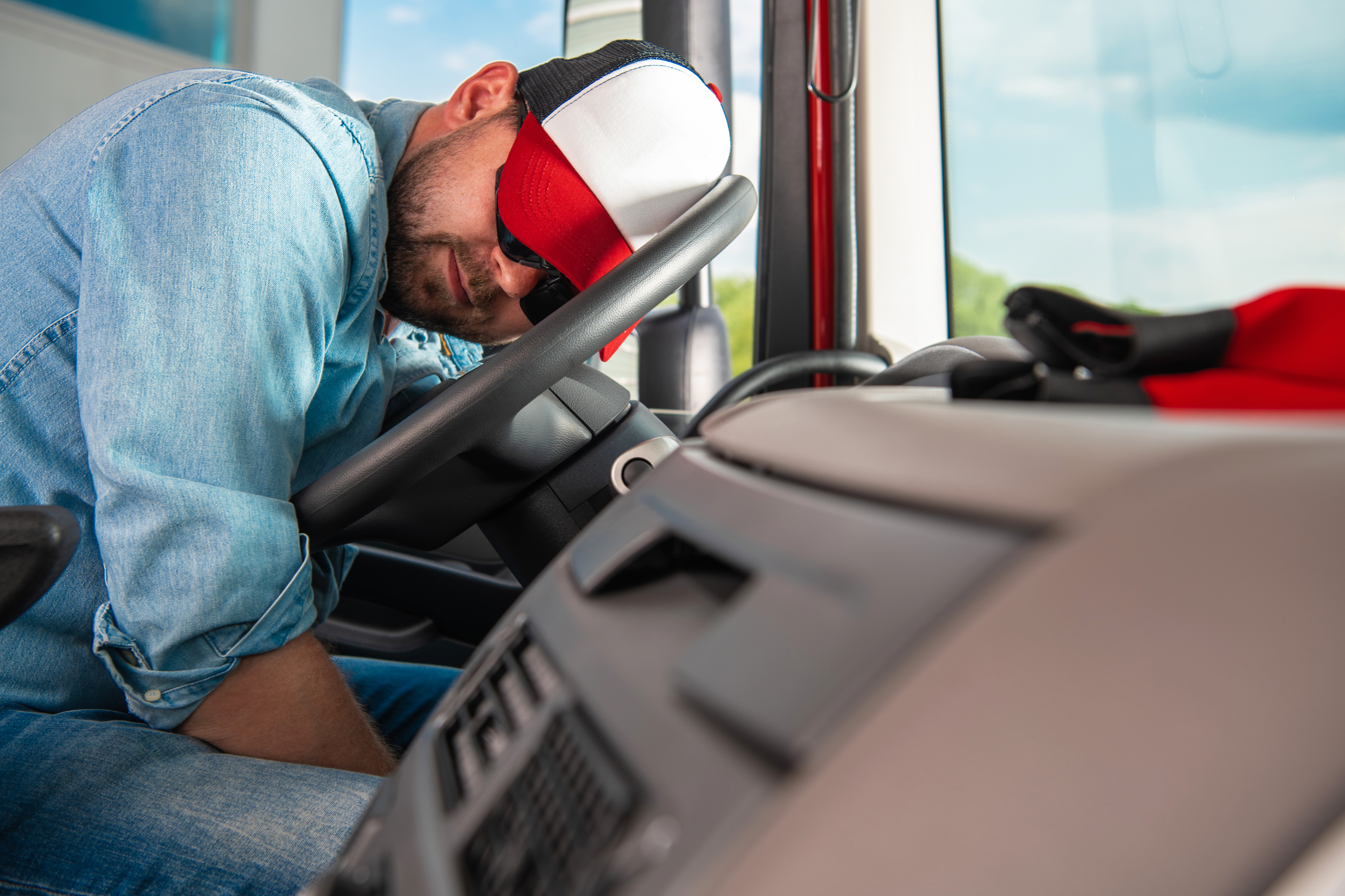 truck driver leaning his head on the steering wheel, sleeping