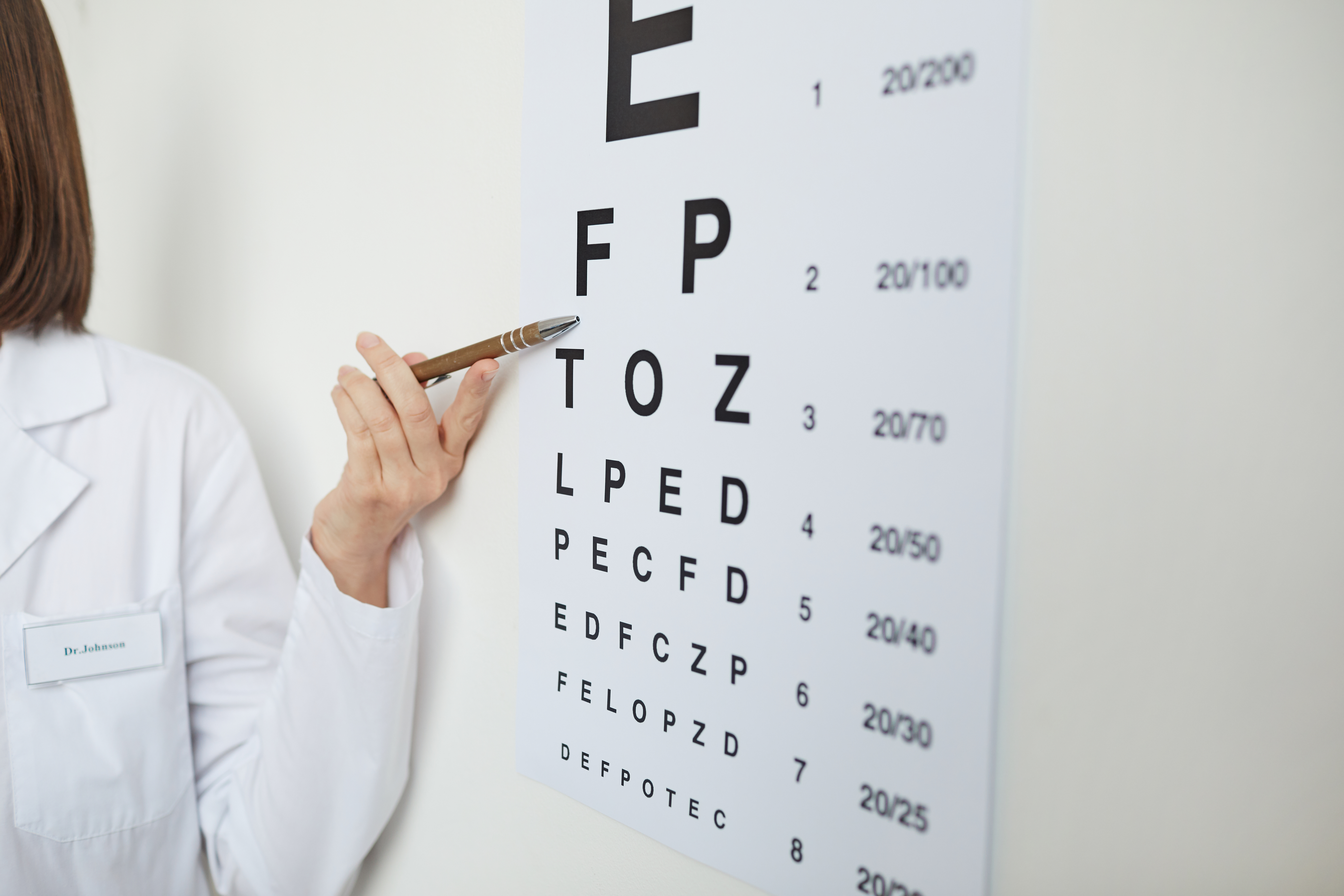 someone out of frame pointing at a letter on an eye exam test