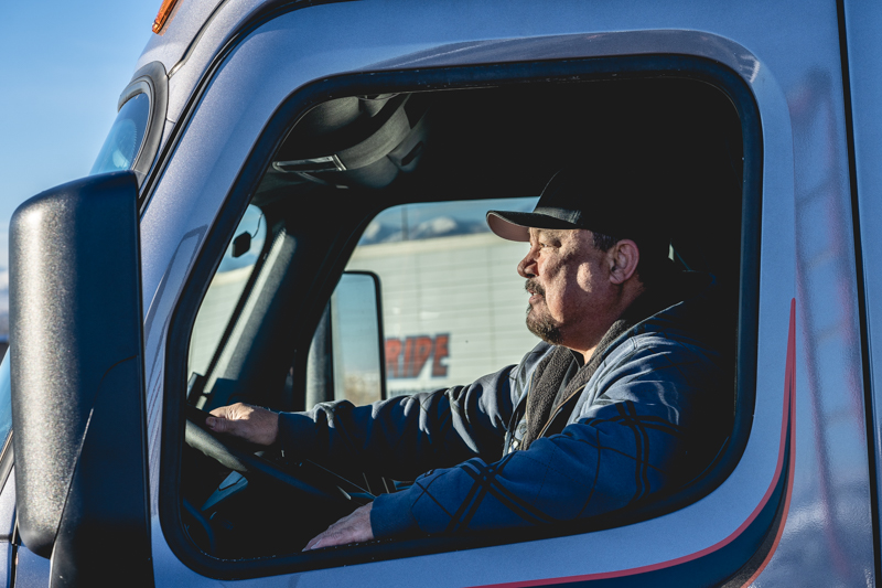 a man in the driver's seat of a pride transport truck looking forward