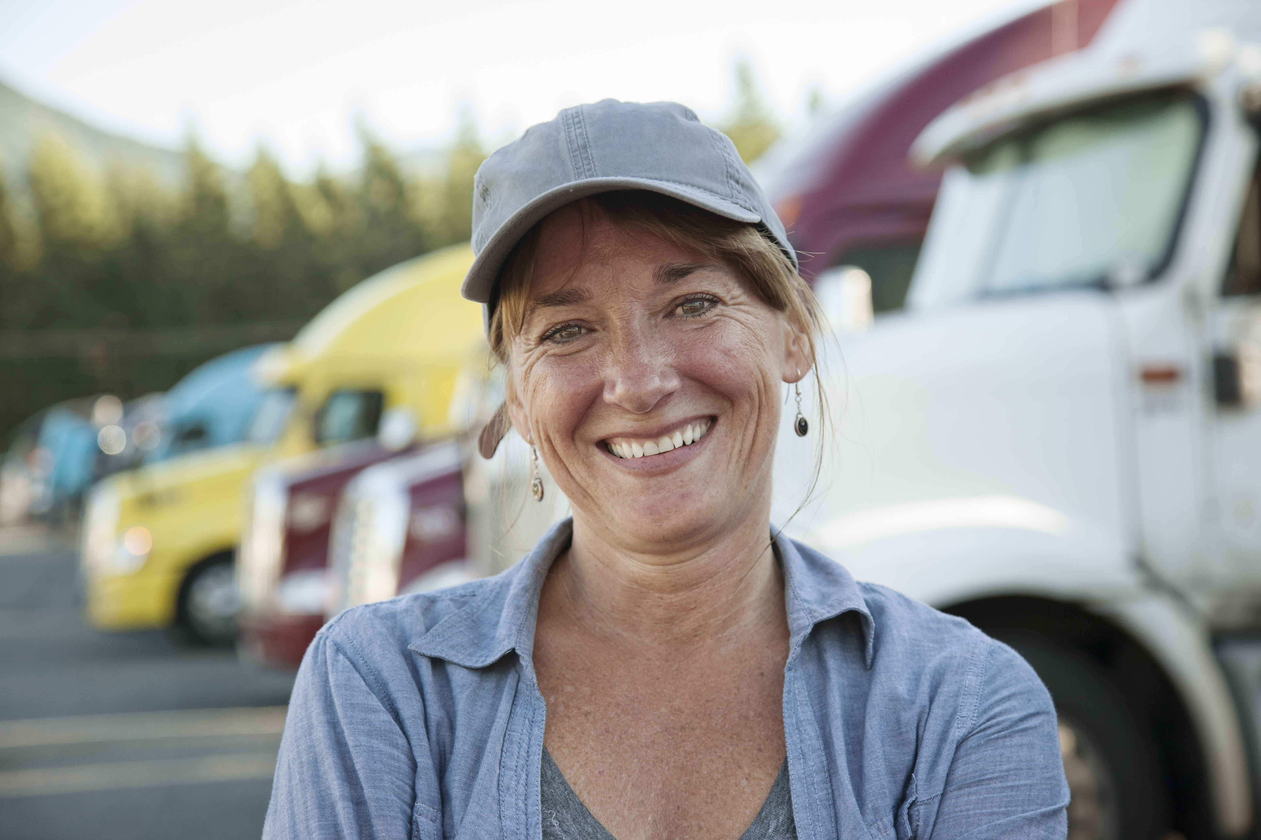 woman smilining in front of multiple 18 wheelers
