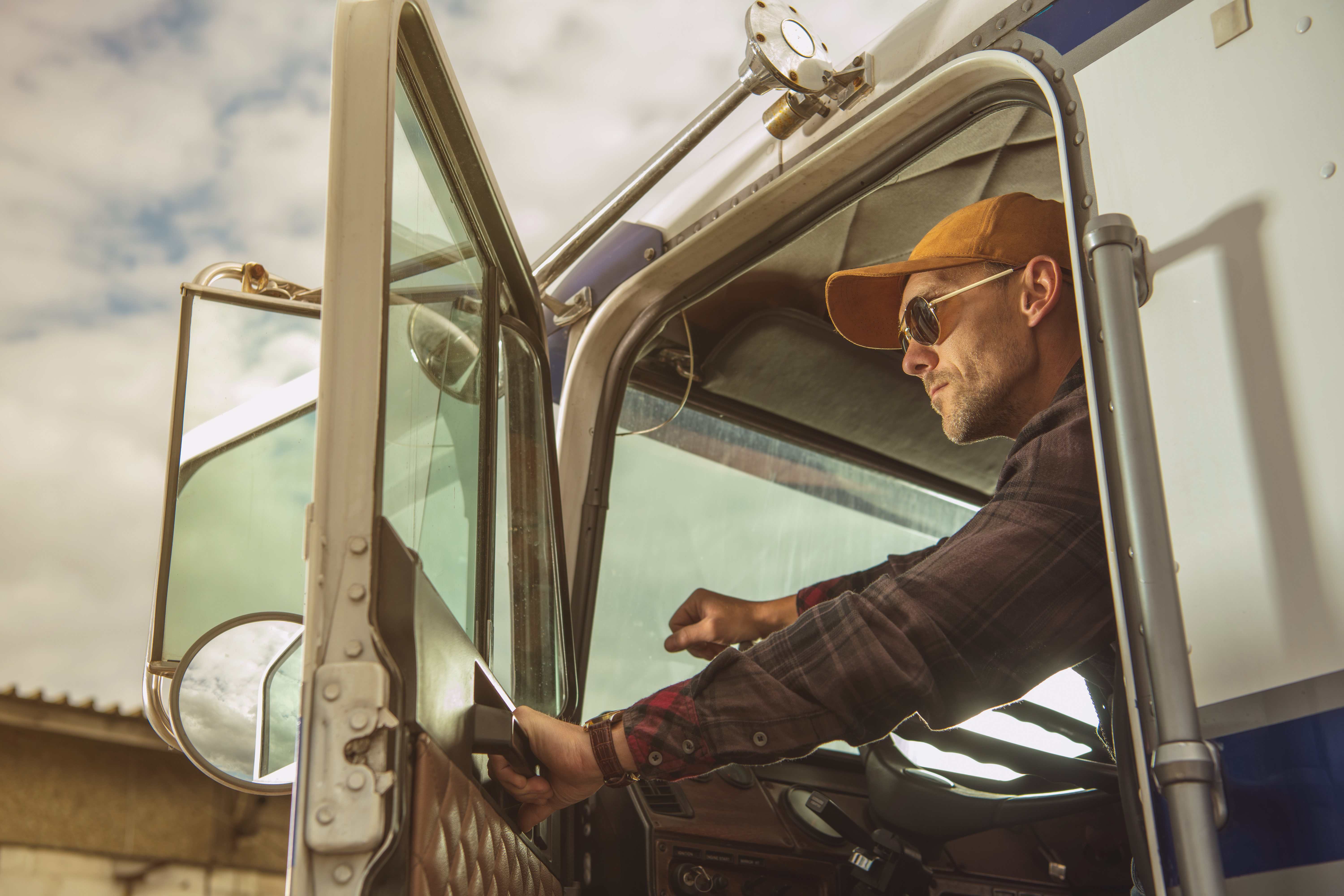 man leaning out of truck with door open and looking into distance