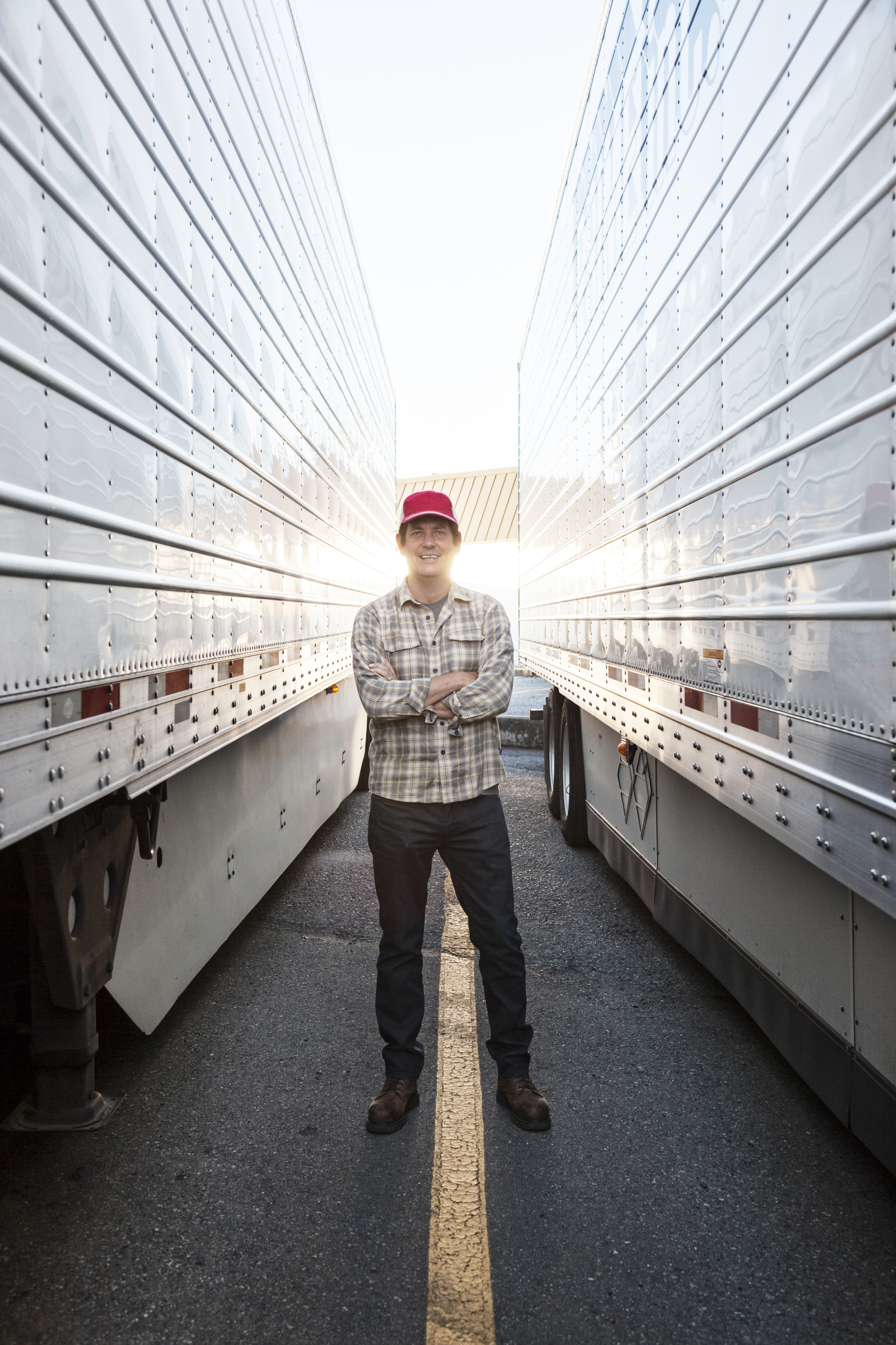 truck driver standing in between two trucks and smiling