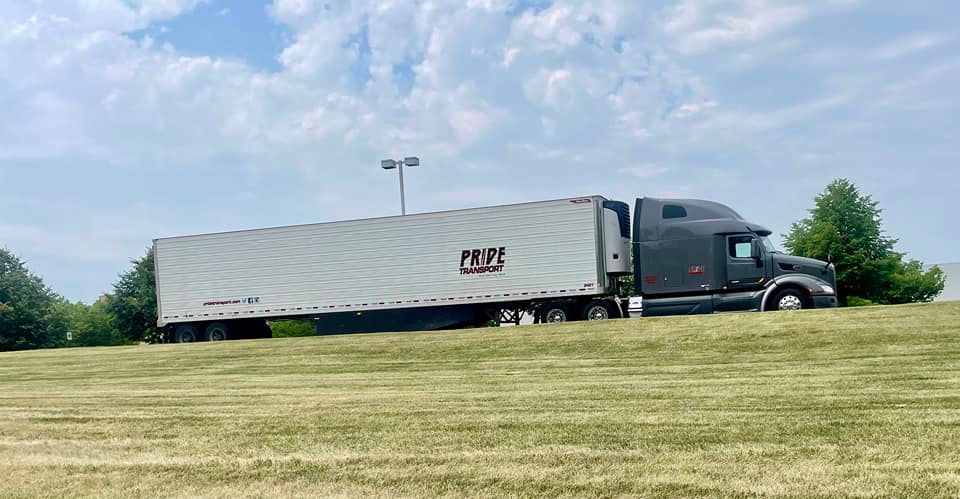 pride transport truck parked on shoulder of road and grass in foreground