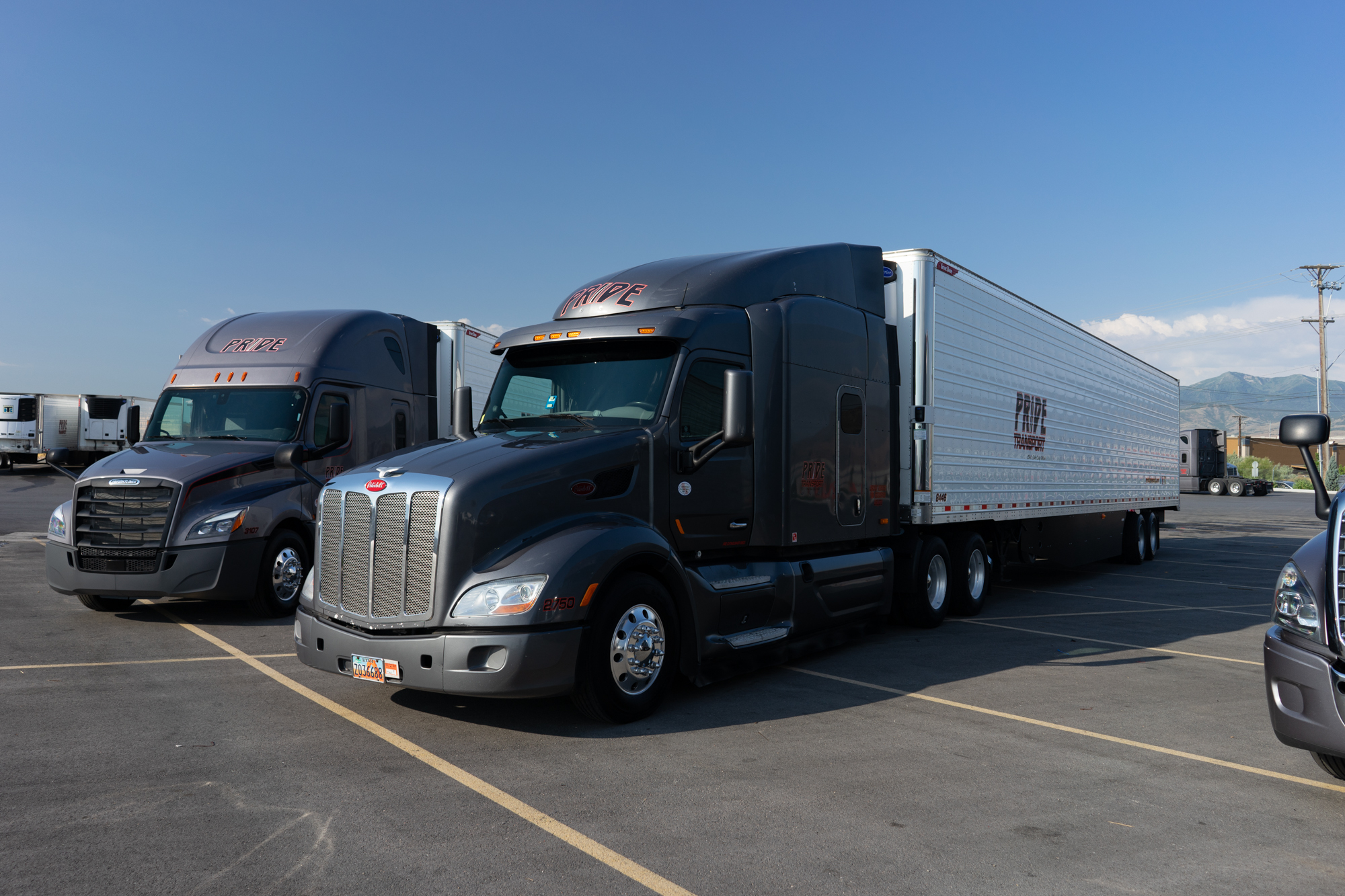 two pride transport grey trucks parked together