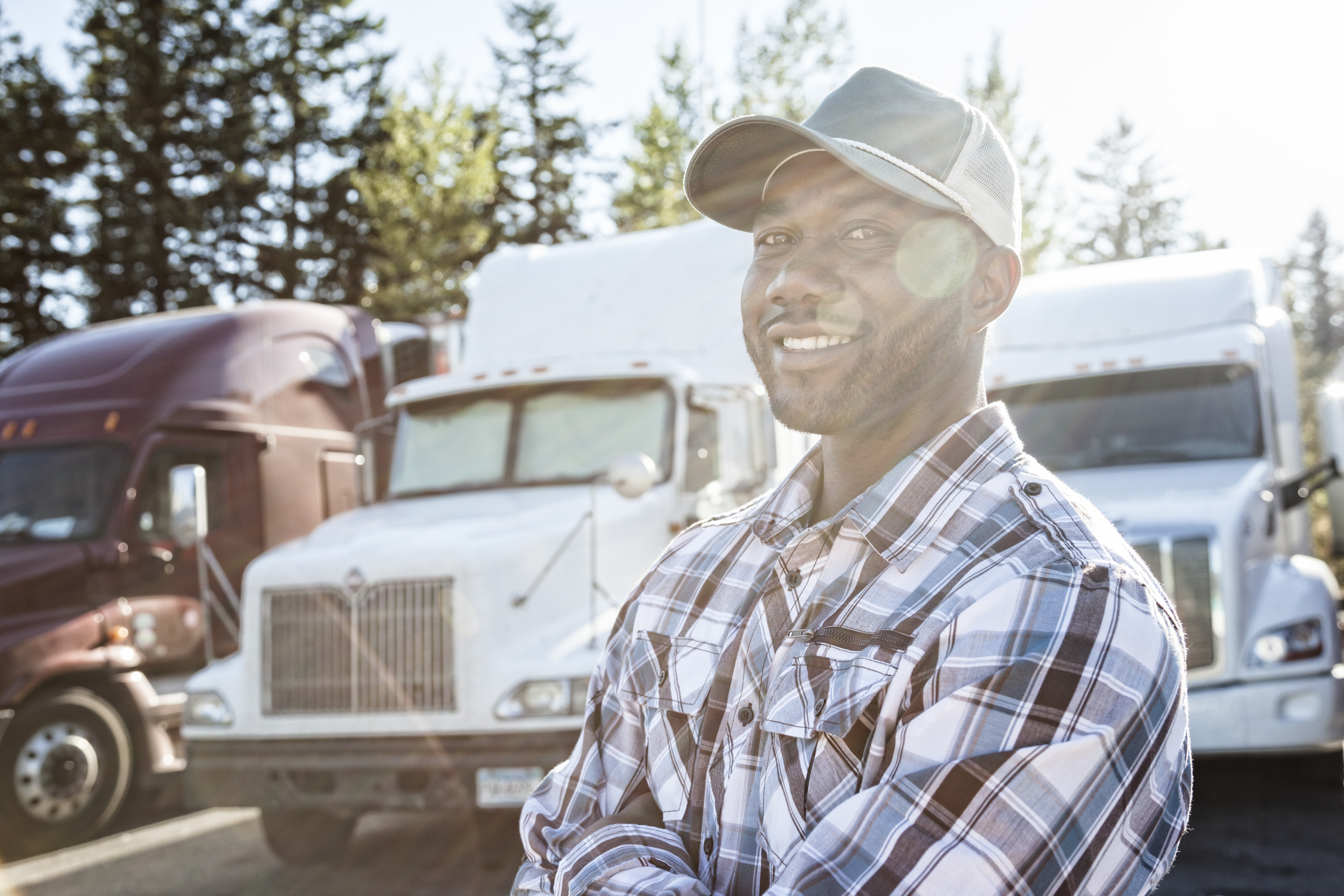 african american man smiling in front of semi truck with arms crossed