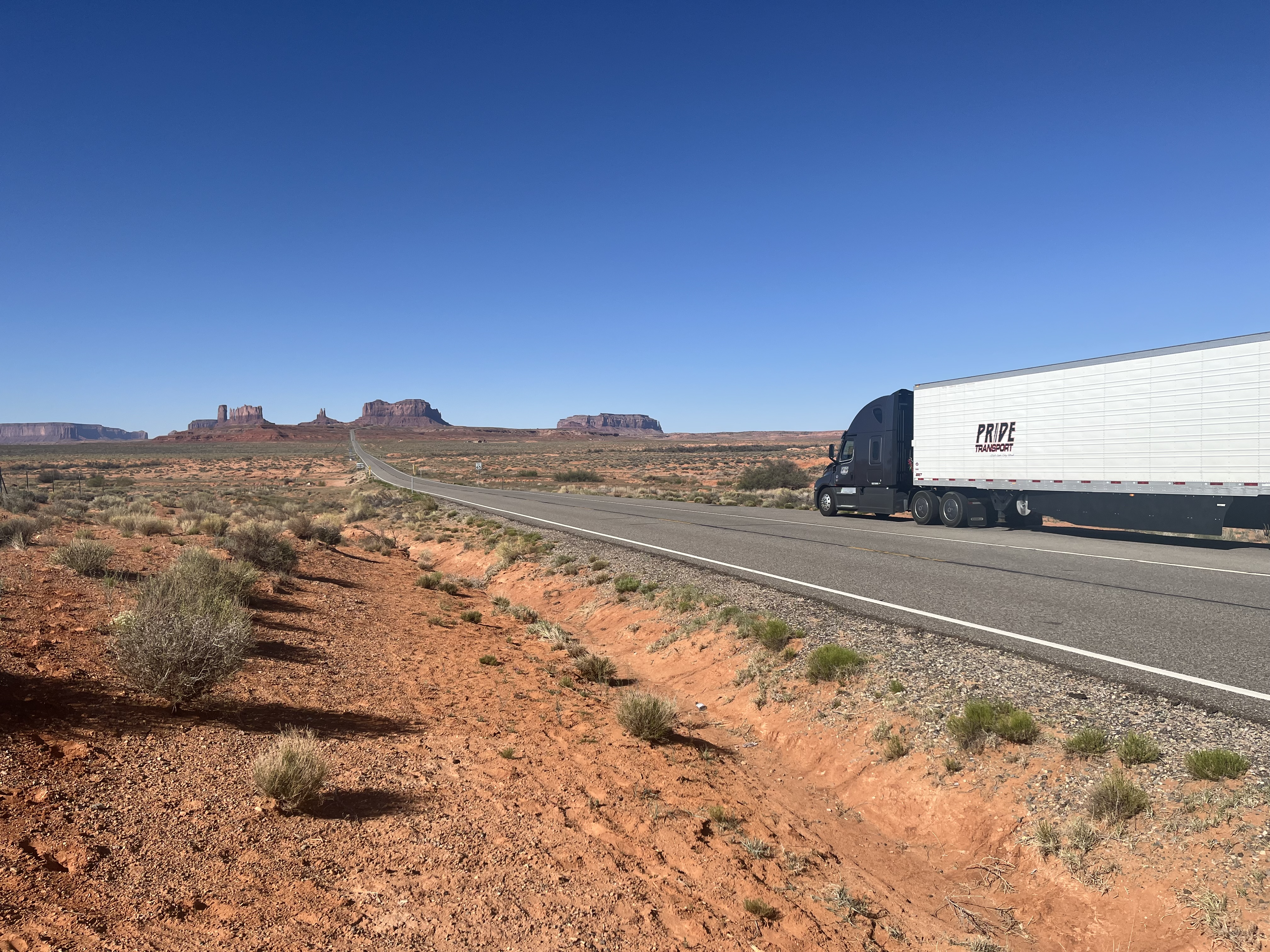 pride transport truck on desert road with red rock in background 