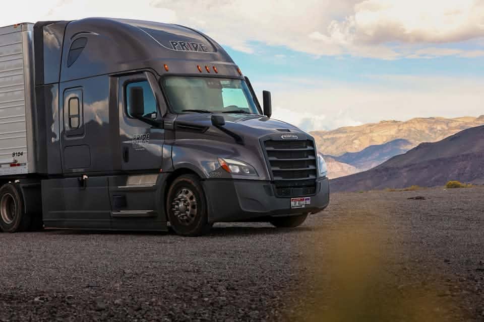 pride transport truck parked with mountainscape in background