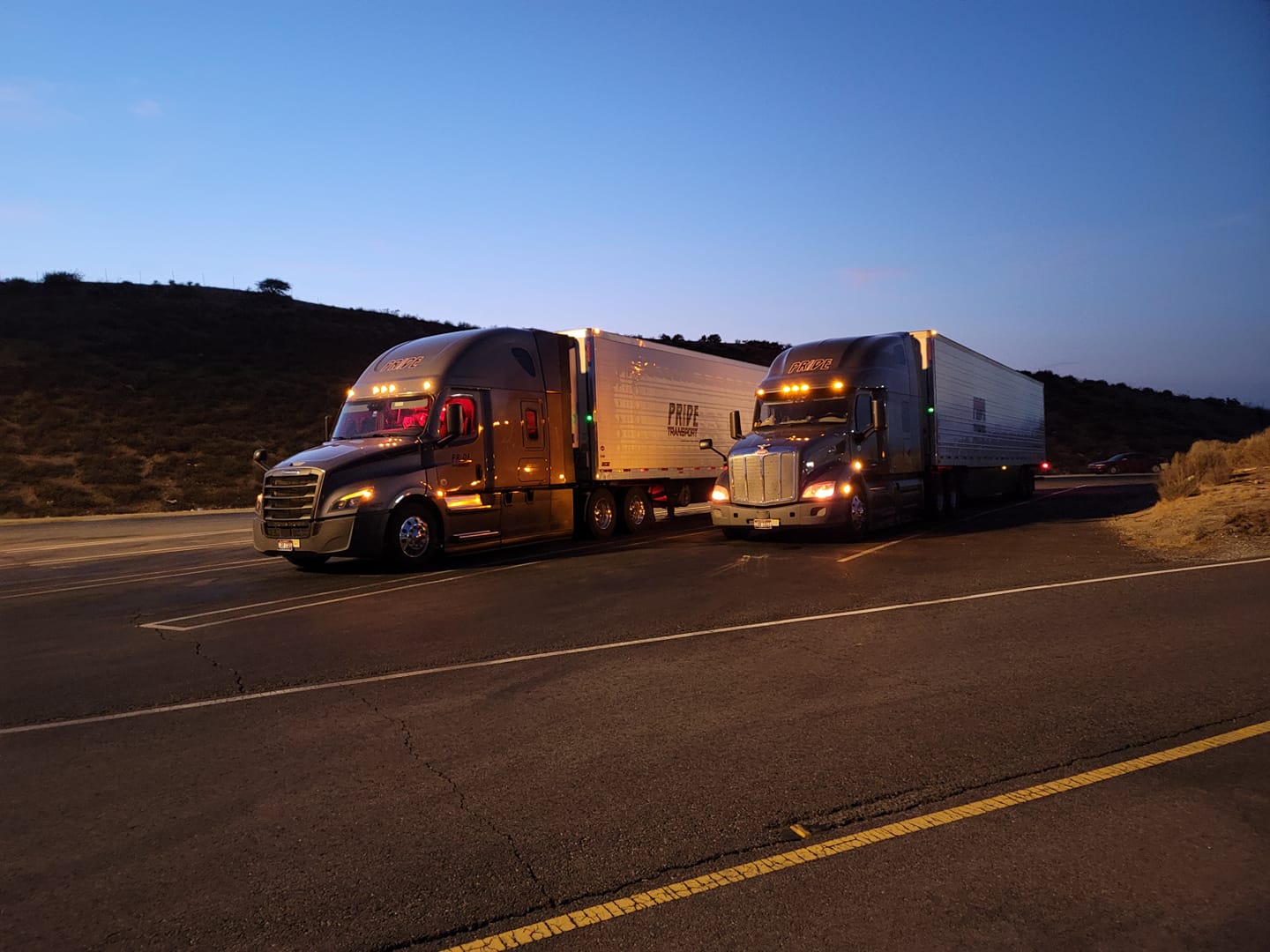 two pride transport trucks parked together