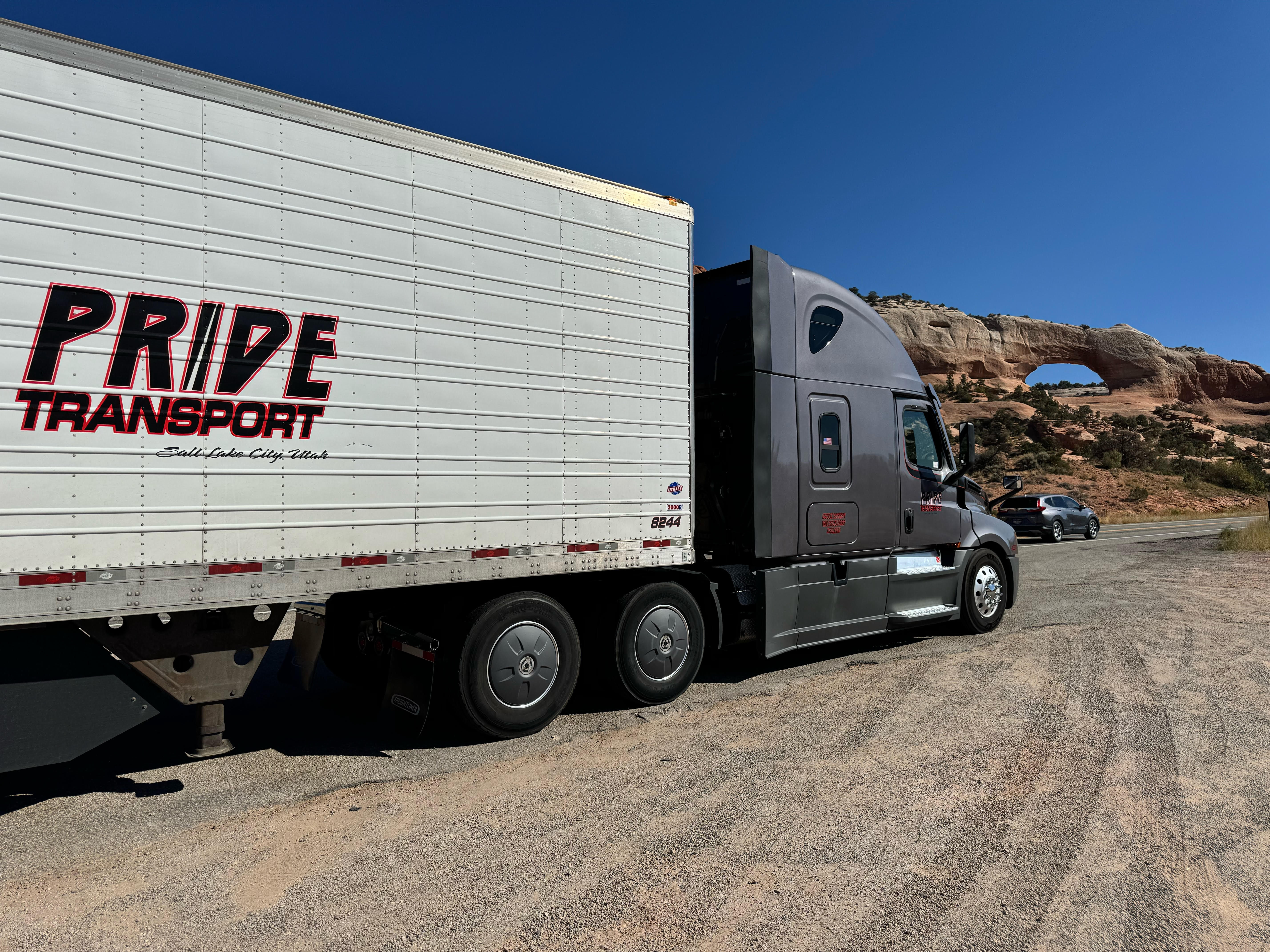 pride transport truck parked on side of road red rock in background