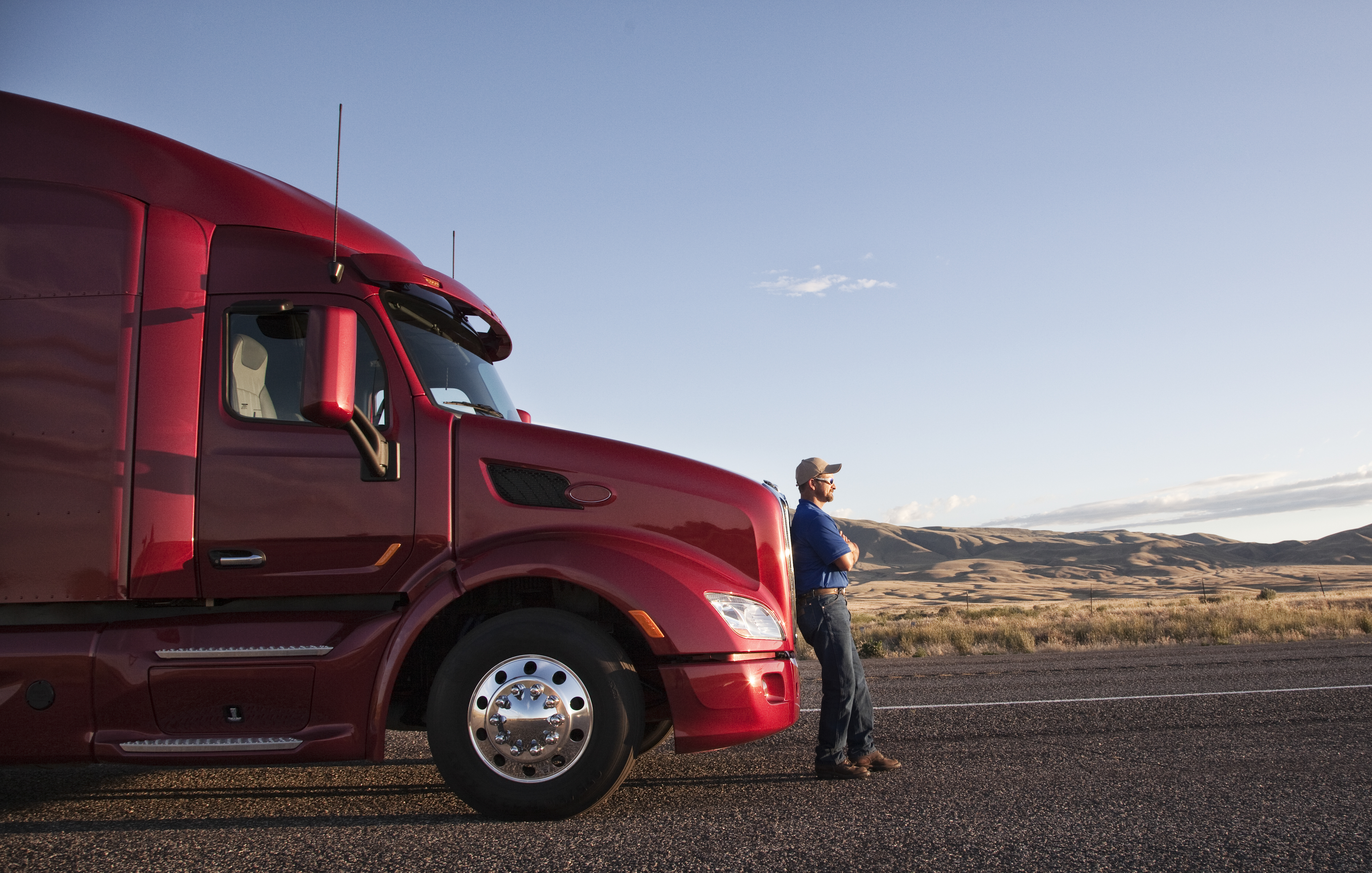 man leaning against front of truck looking out