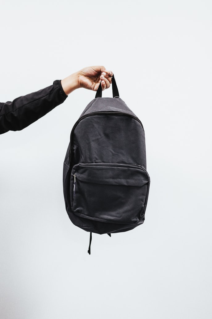 black backpack being held by an arm