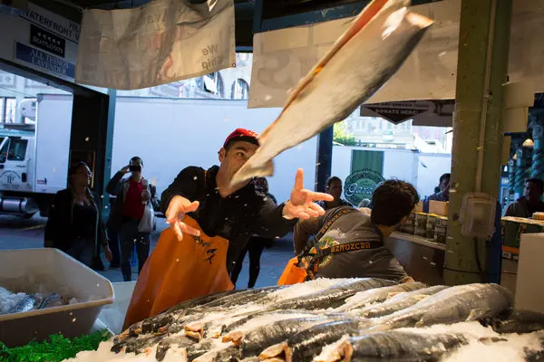 man throwing large fish at pikes place market