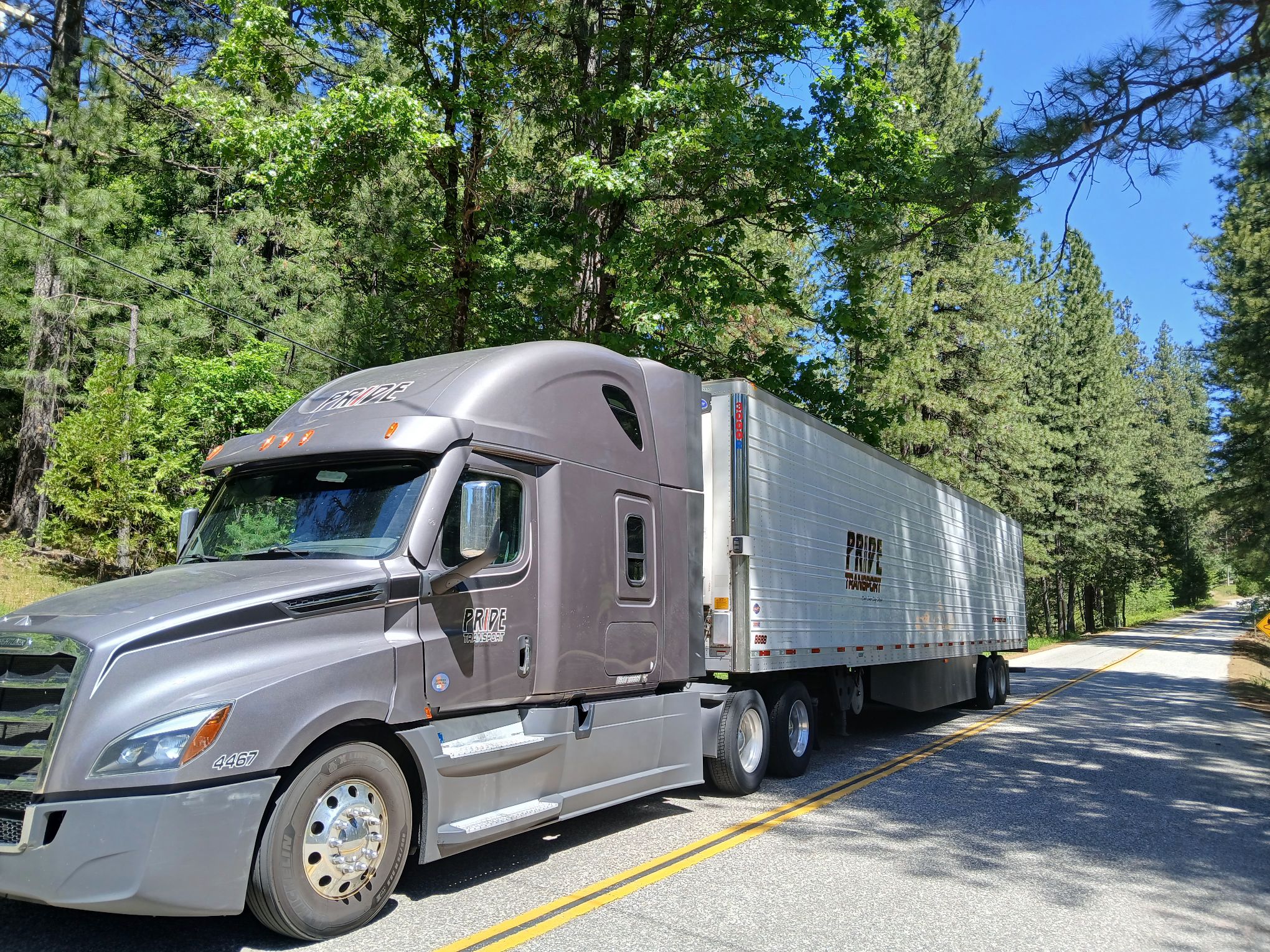 pride transport truck parked with trees in background