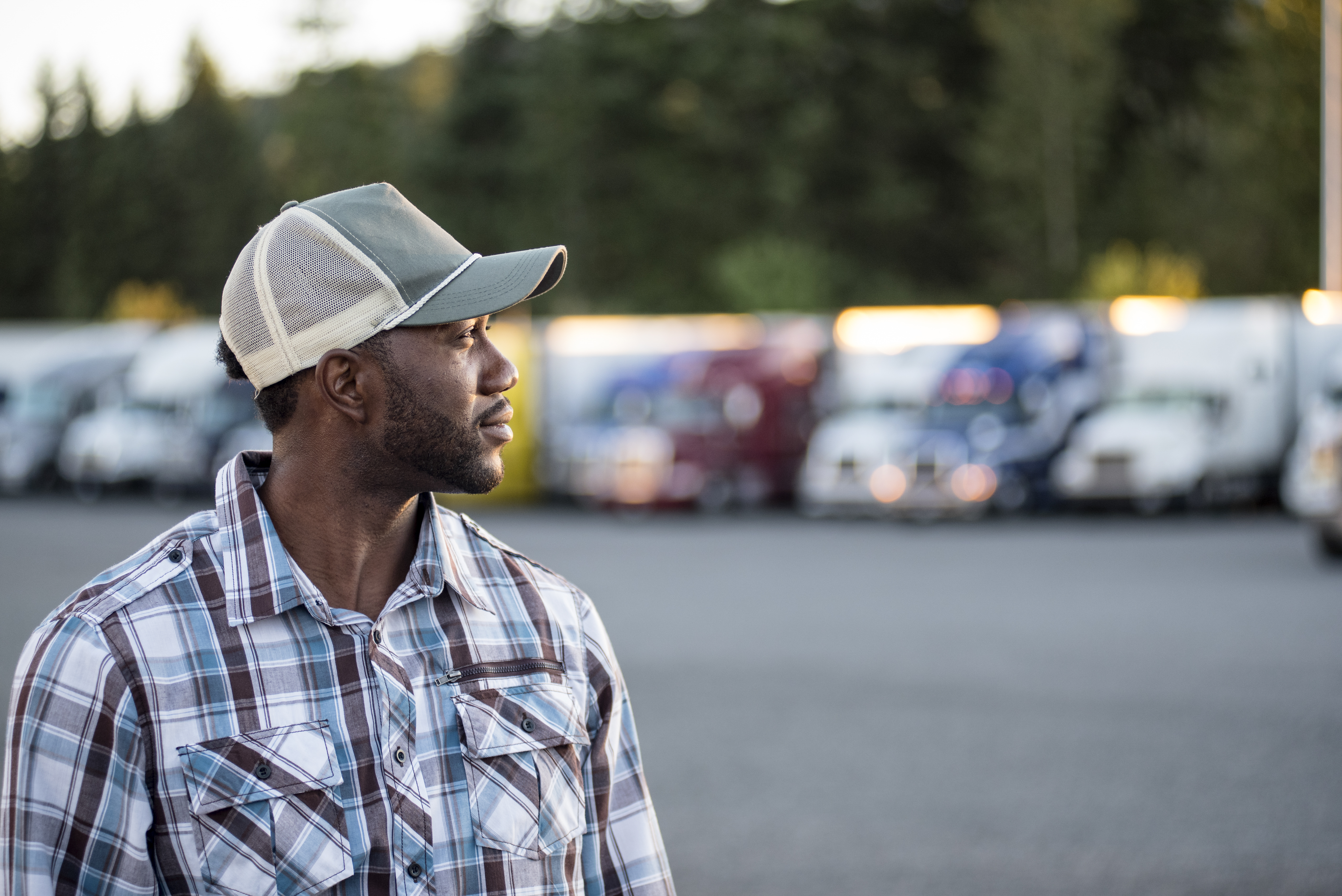 man looking to the side with trucks in the background