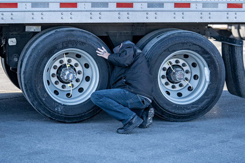 man under trailer checking tires