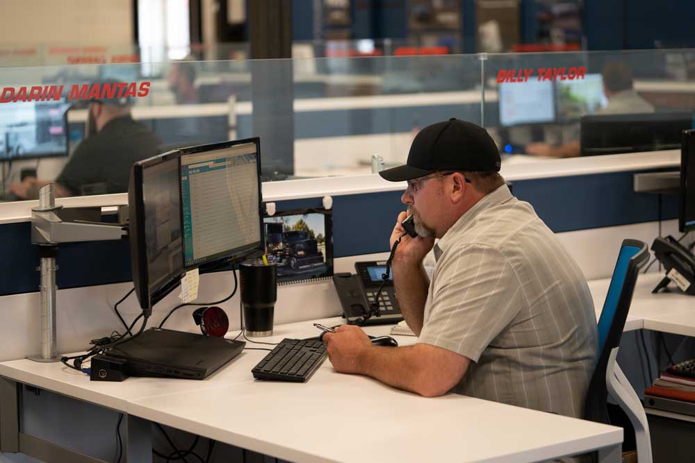 a truck driver manager talks on the phone inside an office