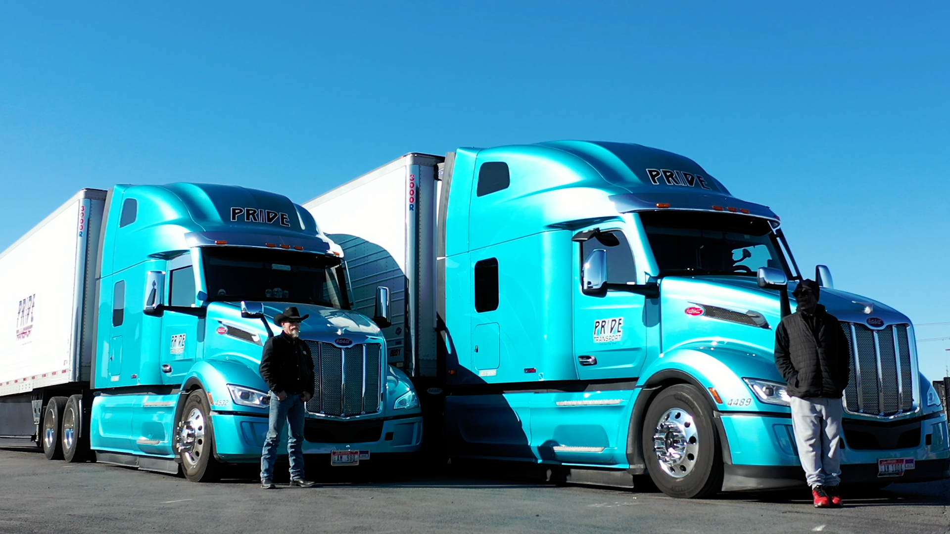 two blue pride transport trucks parked side by side