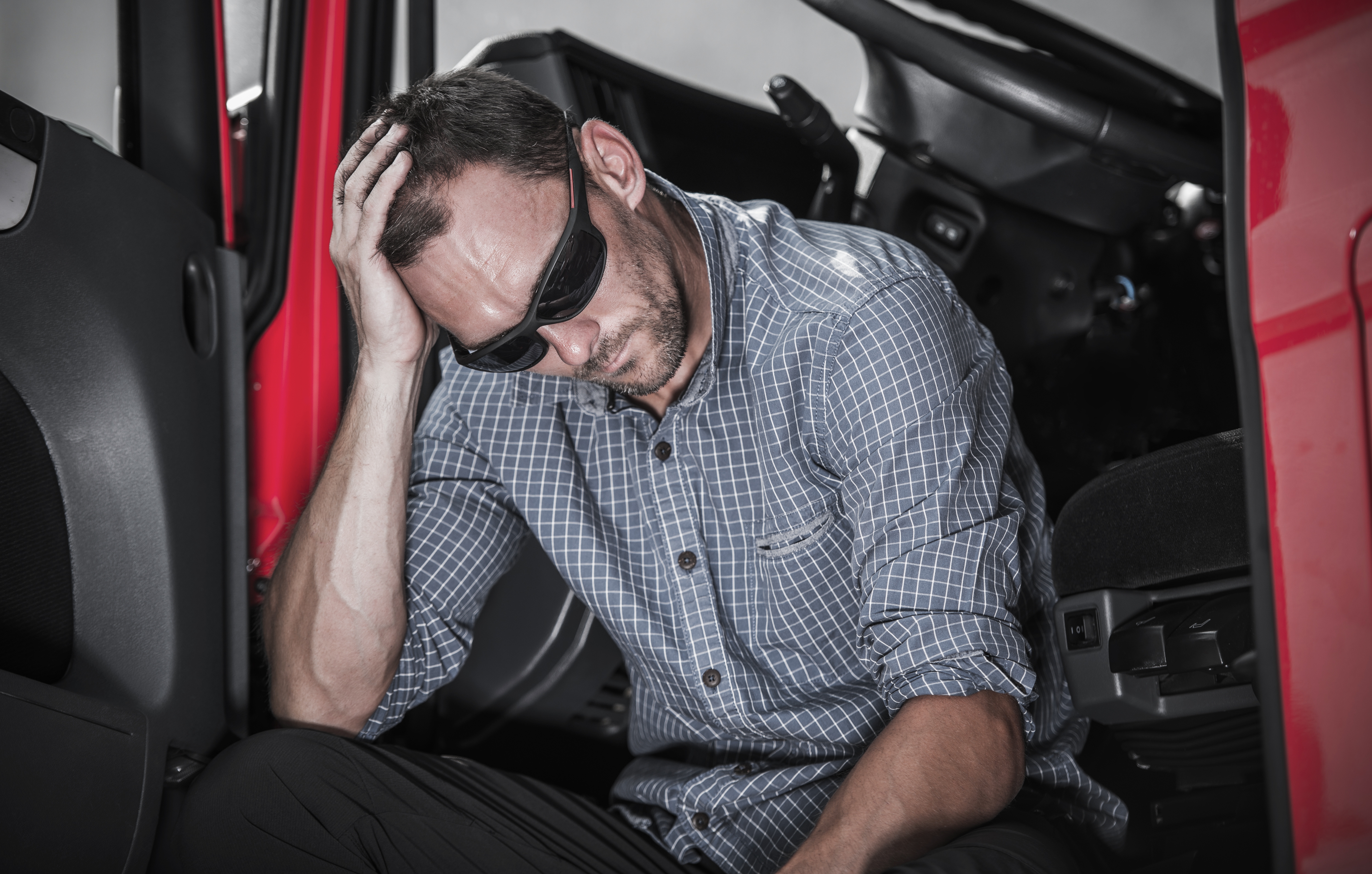 Truck driver appears tired with hand on head