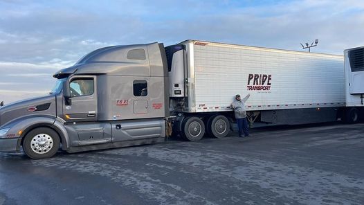 Pride Transport truck with Pride employee standing in front with his arms spread wide