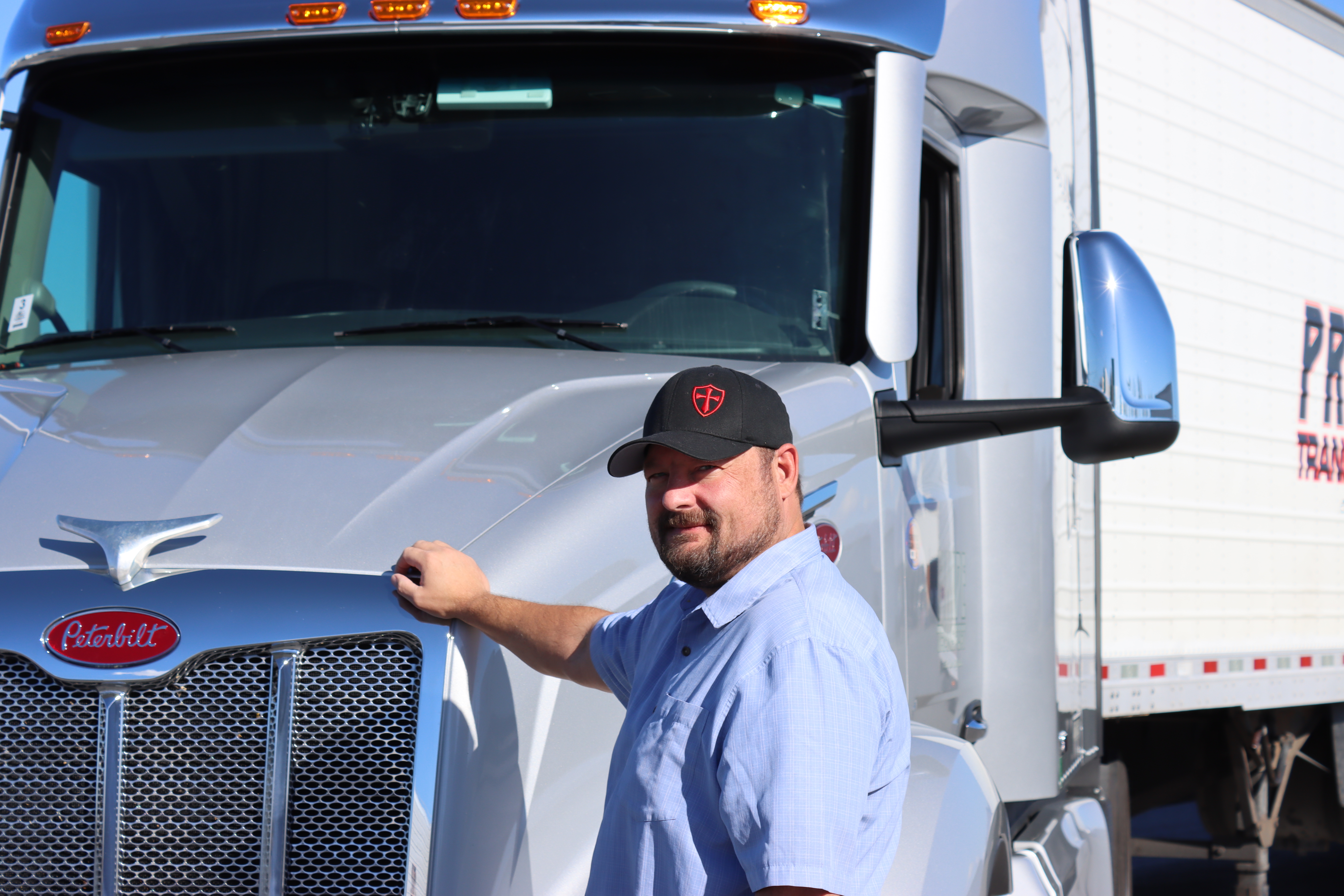 driver standing in front of silver pride transport semi truck