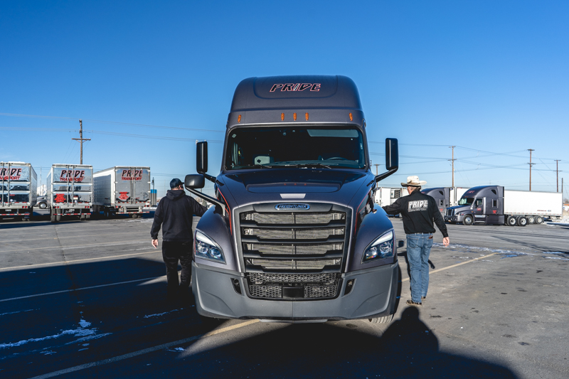 head on photo of pride transport truck and two people opening driver and passenger doors