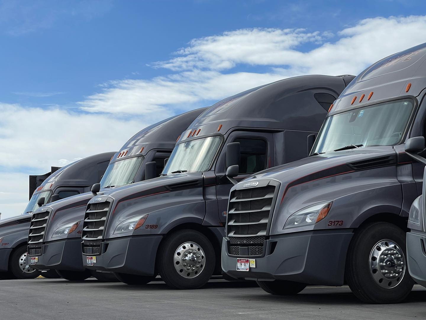 pride transportation semi trucks lined up in a parking lot