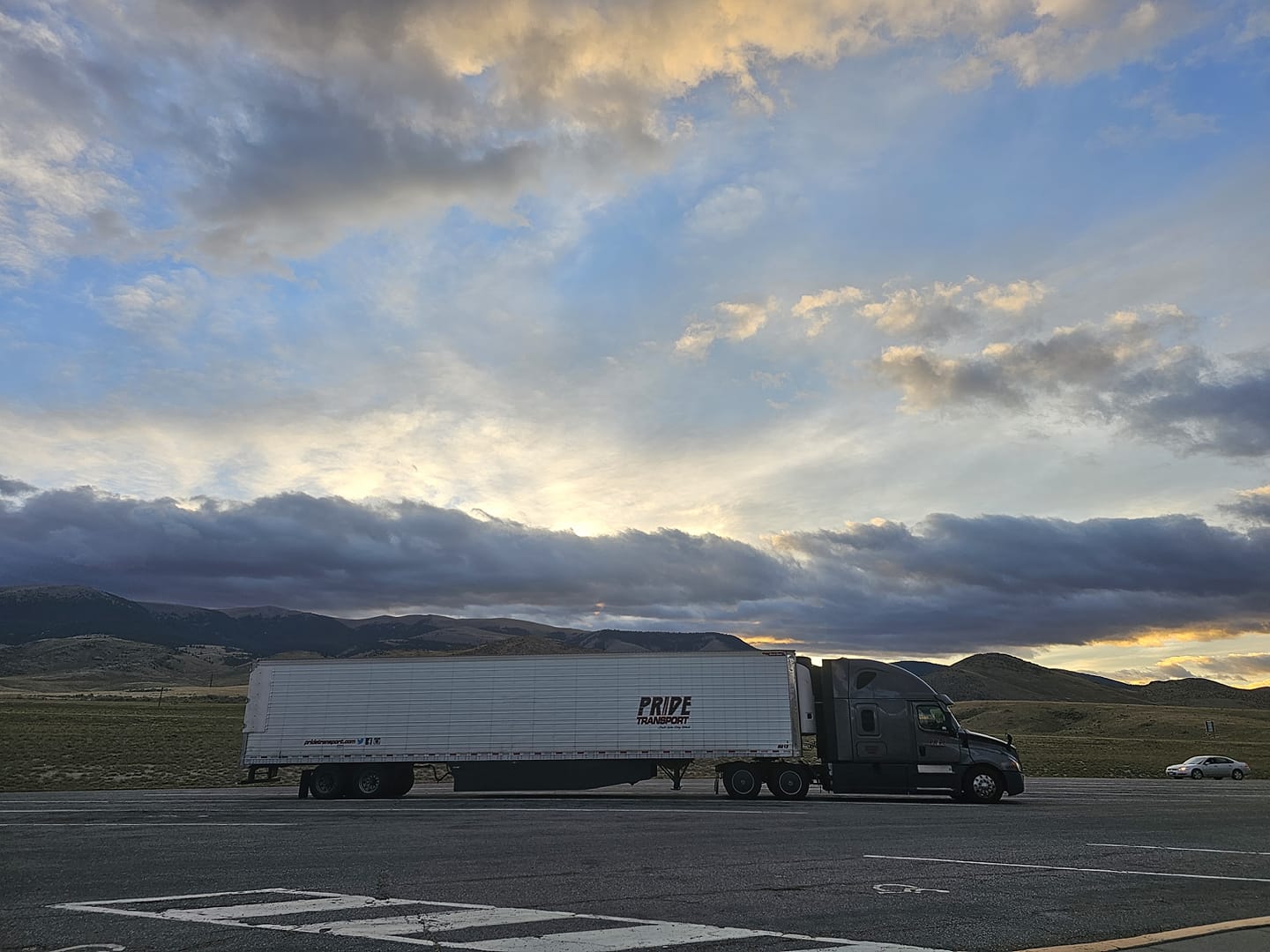 pride transport truck in parking lot with sunset in back