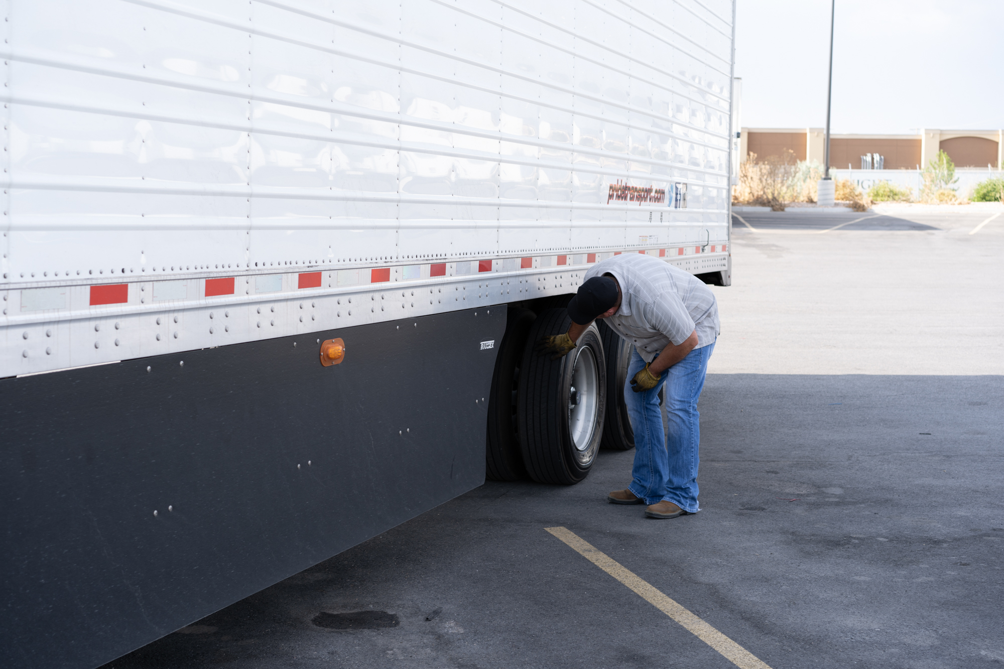 pride transport driver checking semi truck wheels