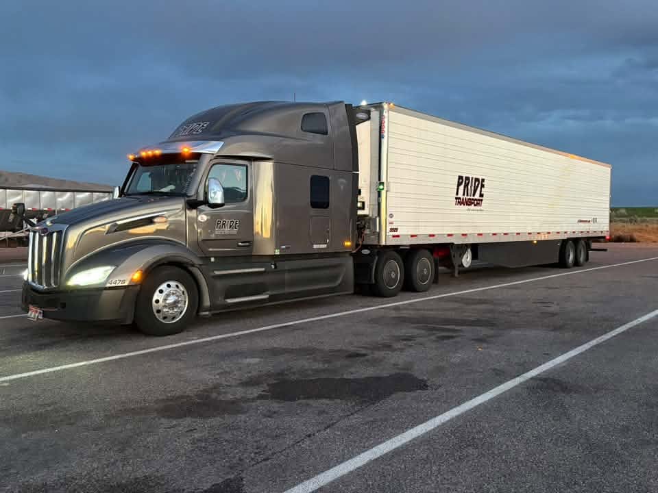 pride transport truck parked in lot sunset