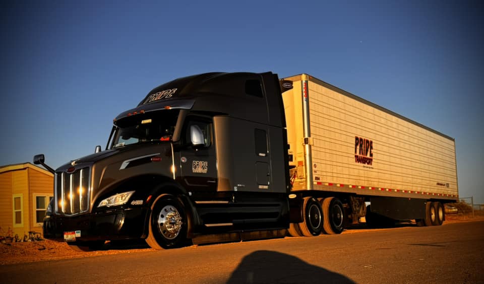 pride transport truck parked on side of road with orange sunset