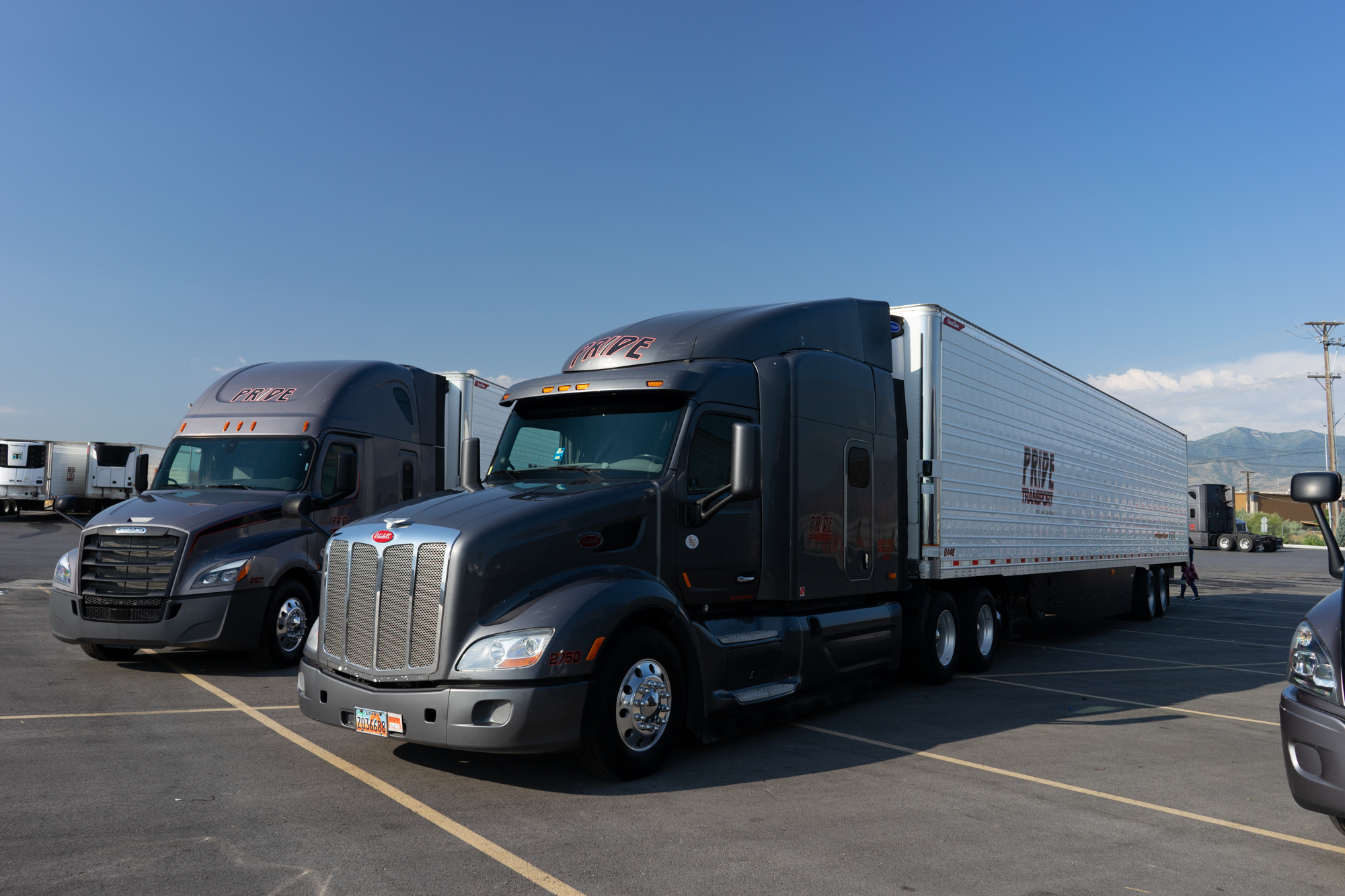 two pride transport trucks parked in lot next to each other