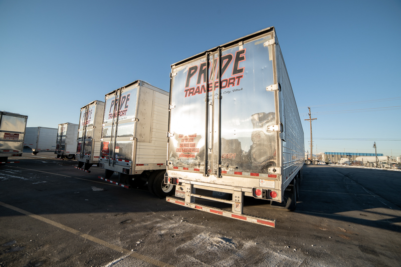 the back ends of five pride transport trucks in a parking lot