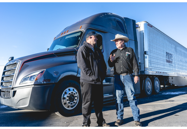 two pride transport employees standing in front of company truck and talking