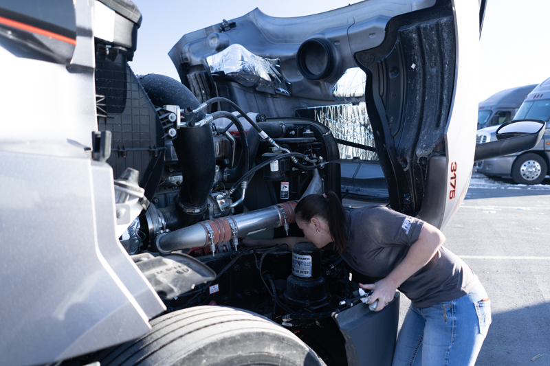female pride transport employee working on truck engine