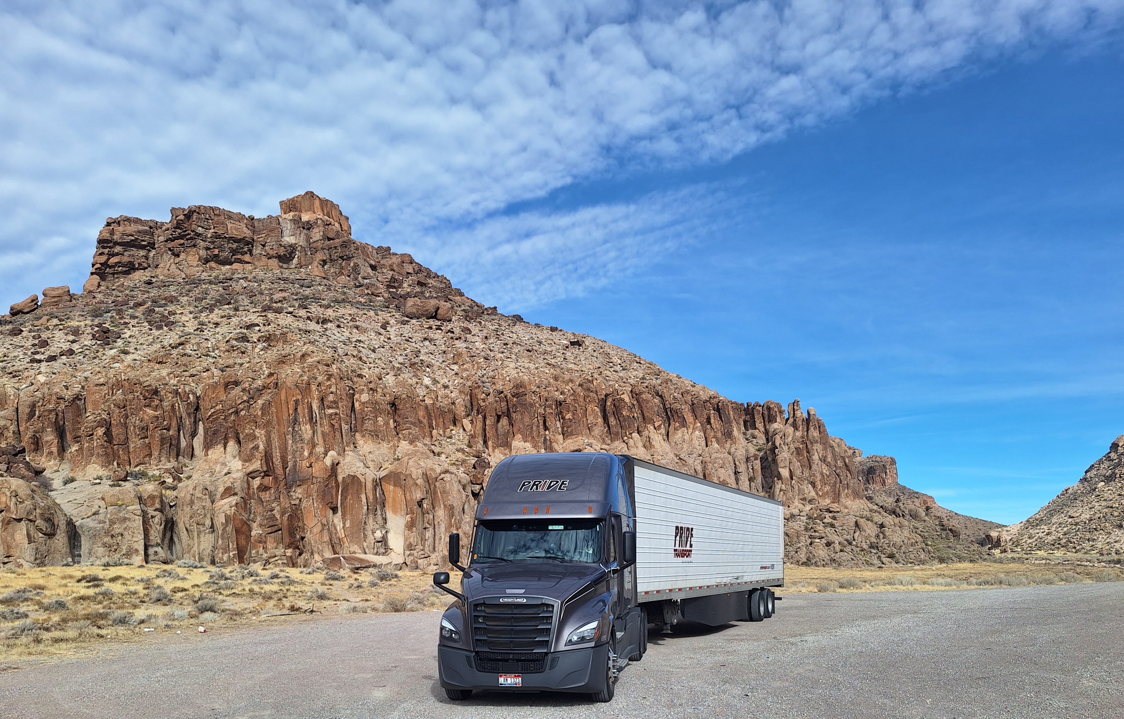 pride transport truck parked in front of red rock mountainscape
