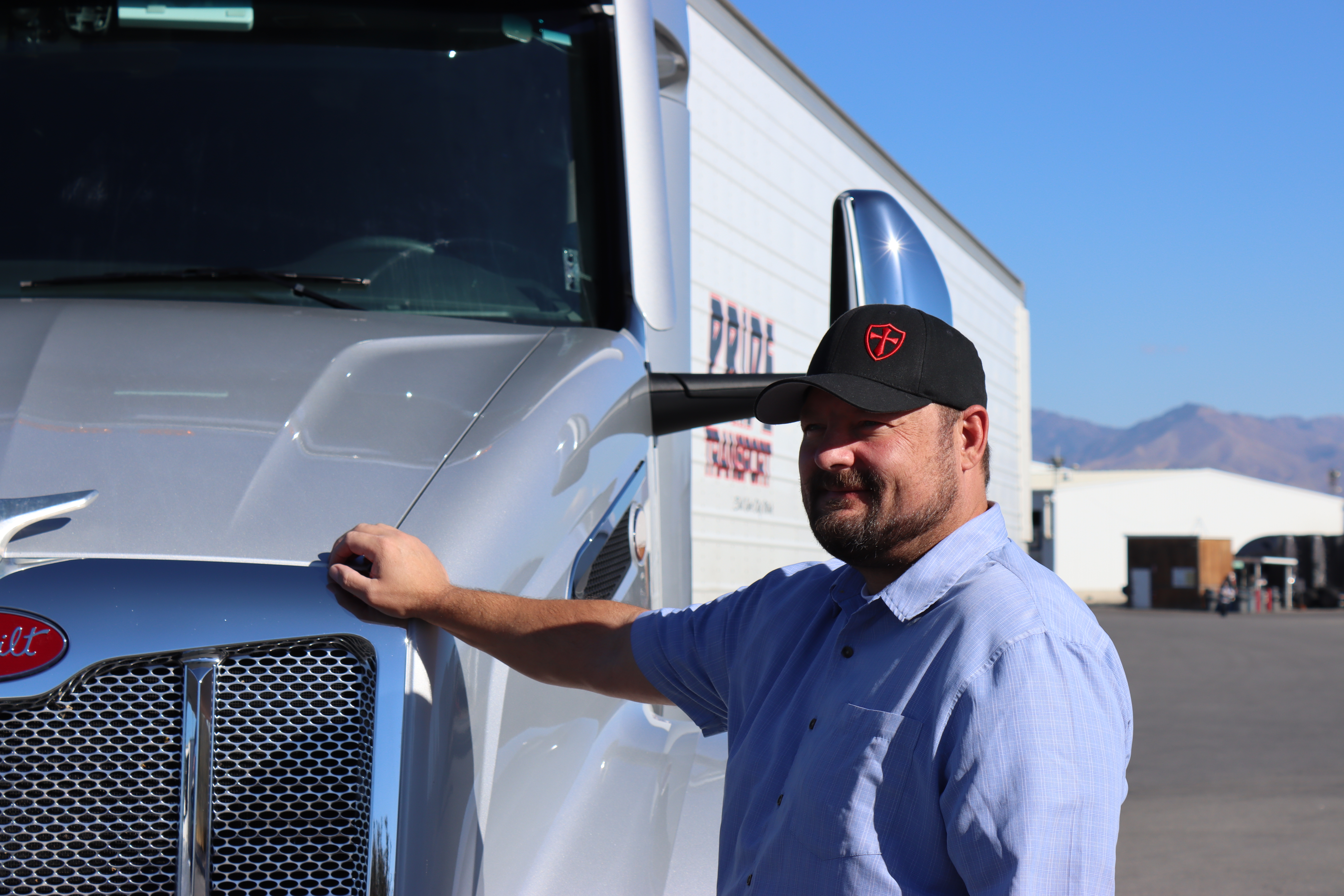 pride transport driver standing next to truck with hand on truck