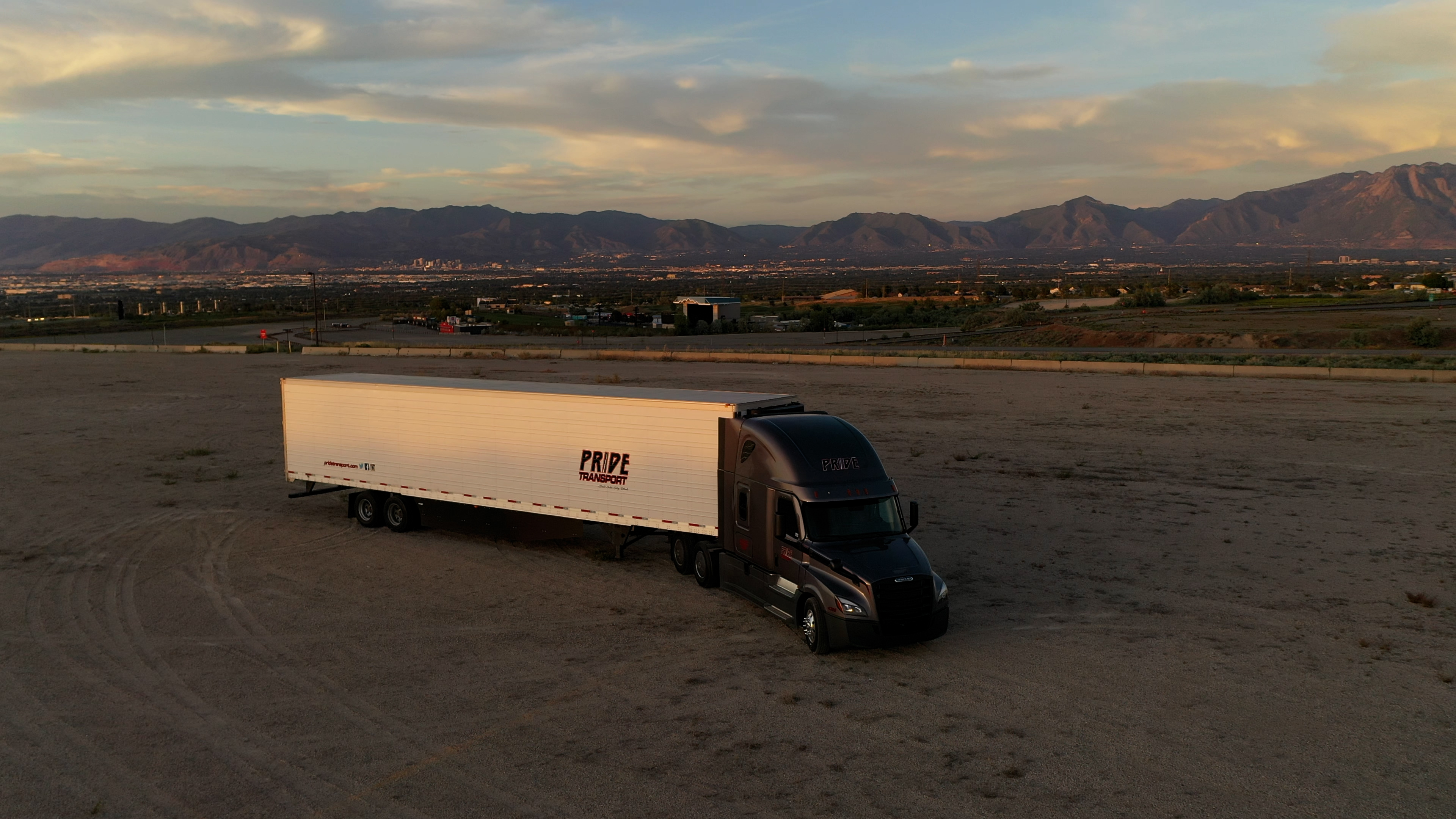 Pride Transport truck parked in a dirt field with a sunset in background