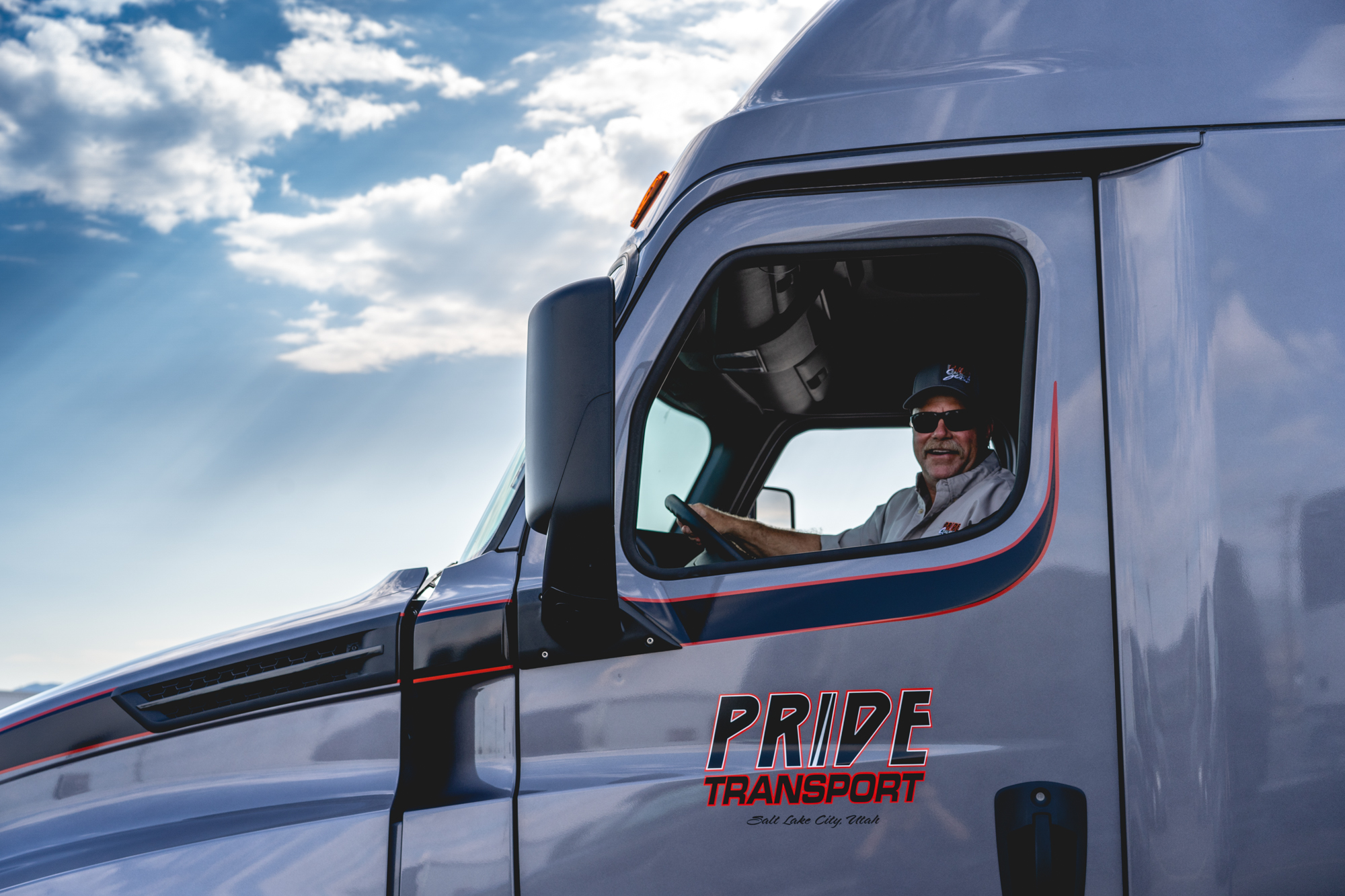 pride transport driver smiling from drivers seat in pride transport truck